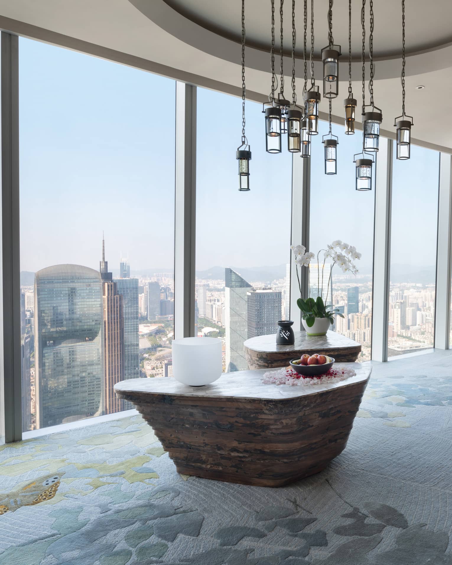 Large soaking tub filled with flower petals overlooking the cityscape from floor-to-ceiling windows