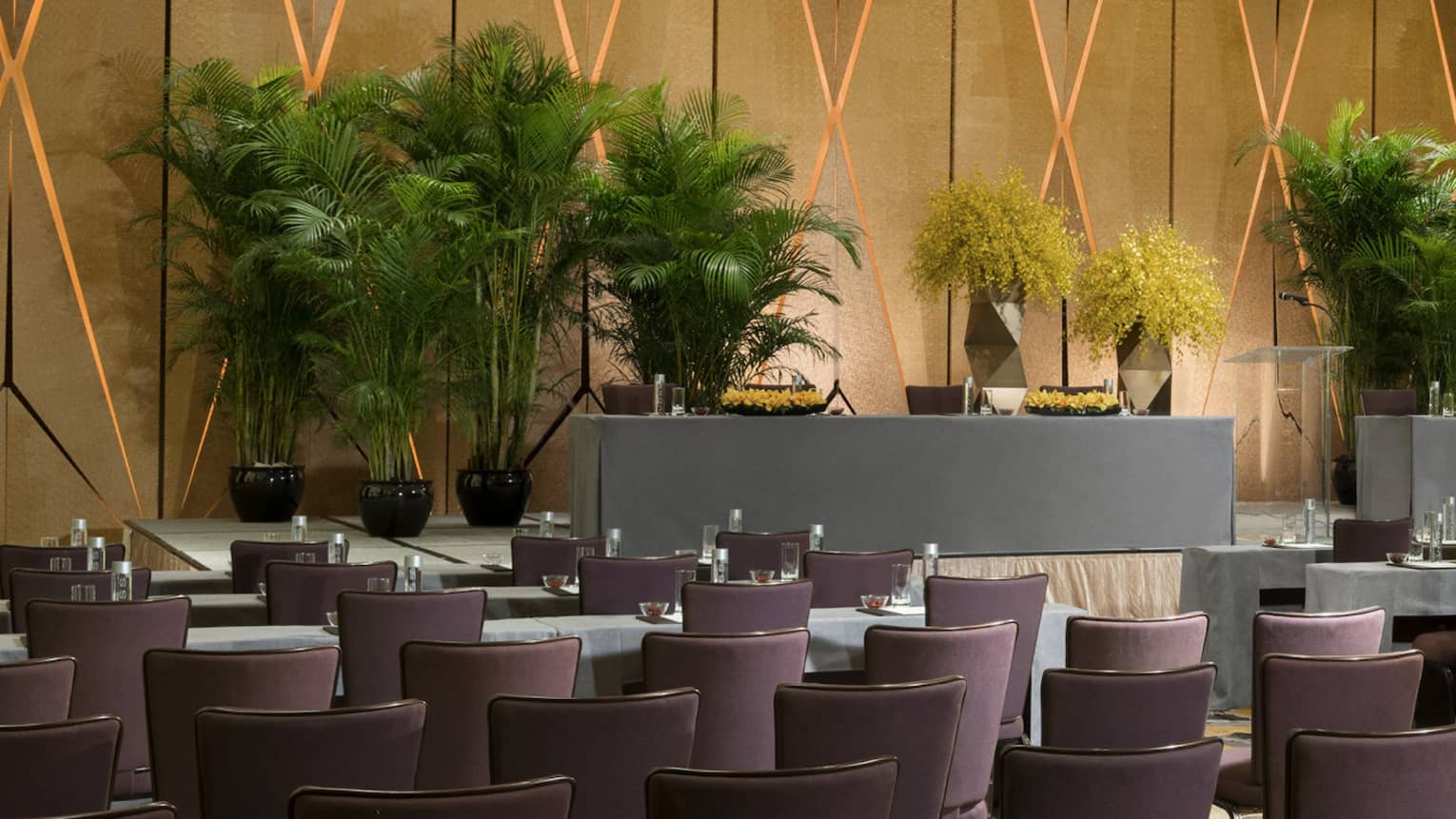 Pearl Ballroom conference with rows of meeting tables facing podium with potted trees 