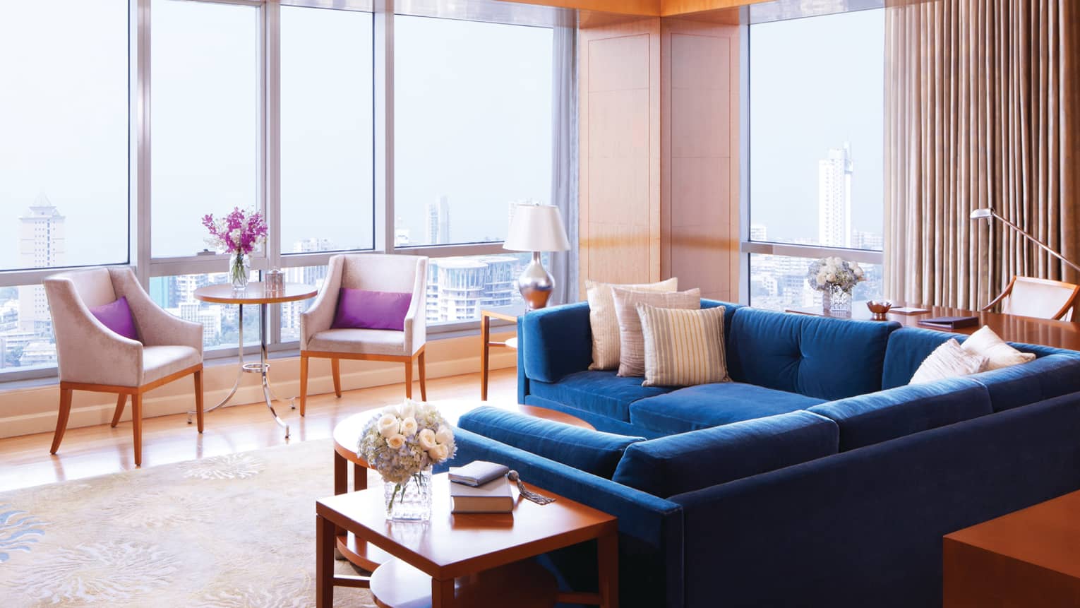 Deluxe Suite-Sea room with blue sectional sofa by floor-to-ceiling sunny windows, chairs