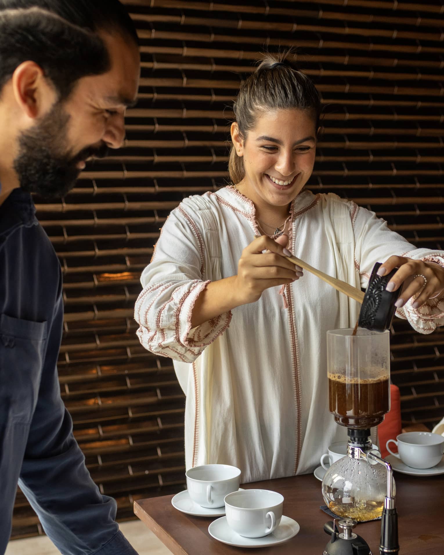 Two women and a man making coffee.