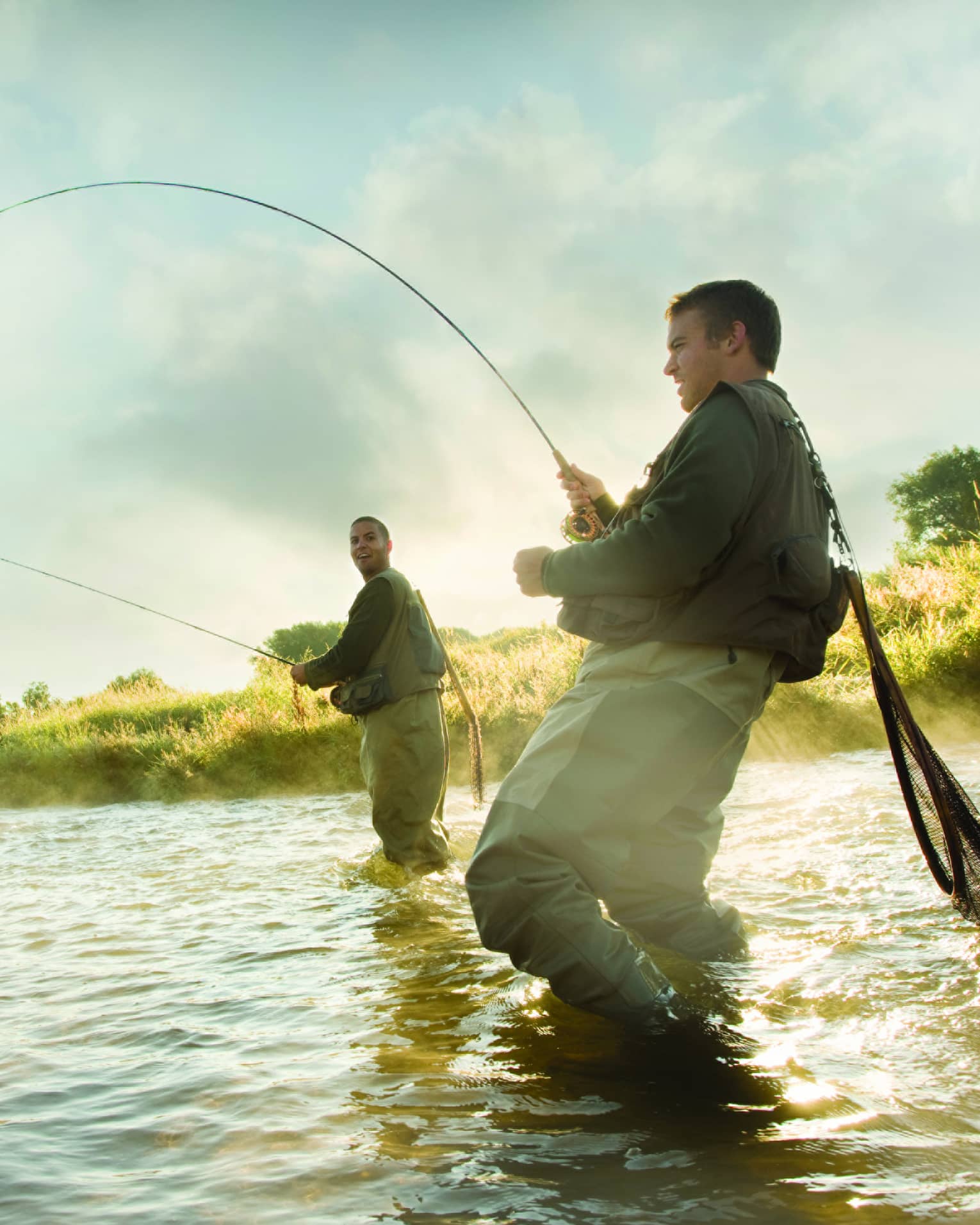 Two men standing in the water, holding rods fly fishing 