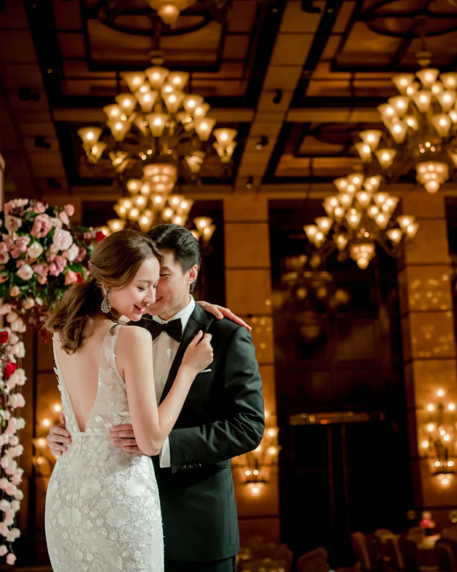 Bride and groom embrace at wedding ceremony in banquet room with lights