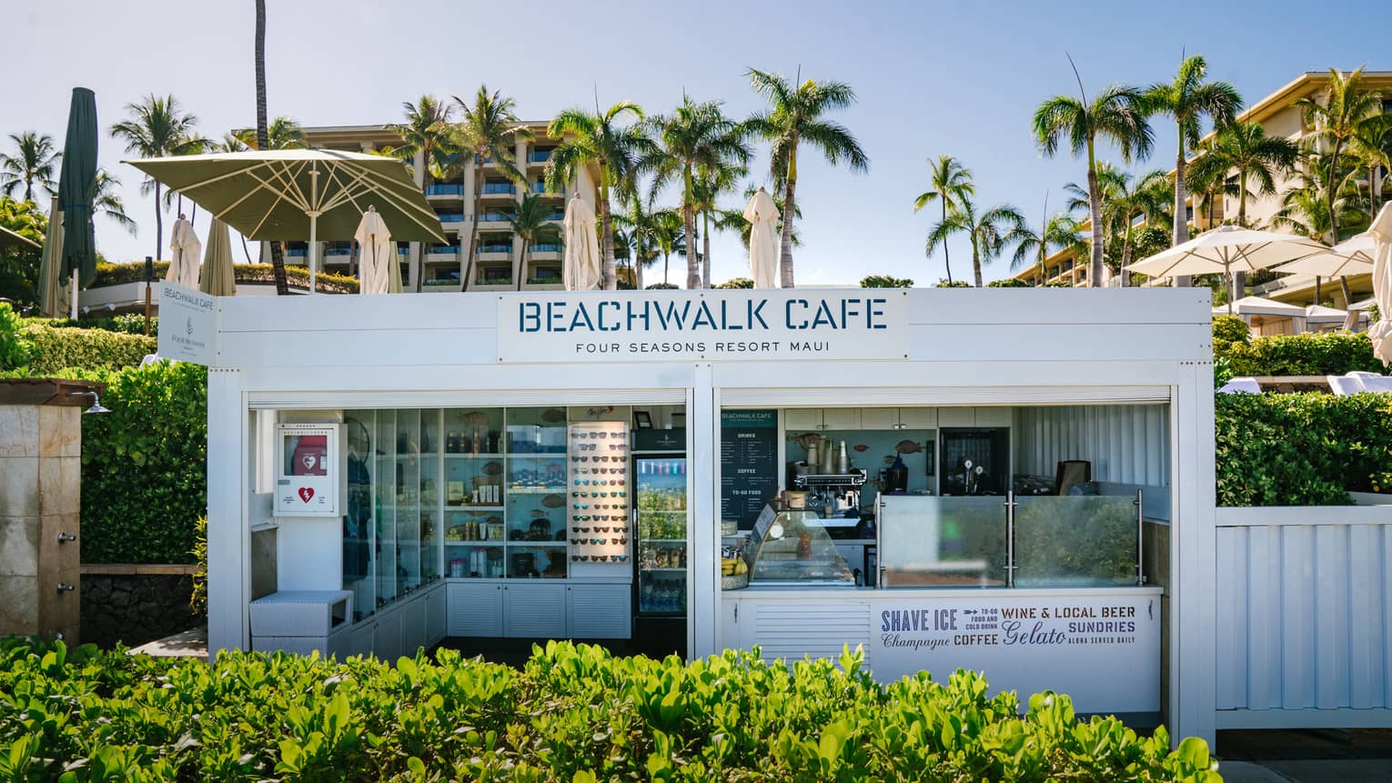 A view of Beachwalk Café, Four Seasons Resort Maui at Wailea, sitting on the scenic Wailea Coastal Walk with palms hanging above it