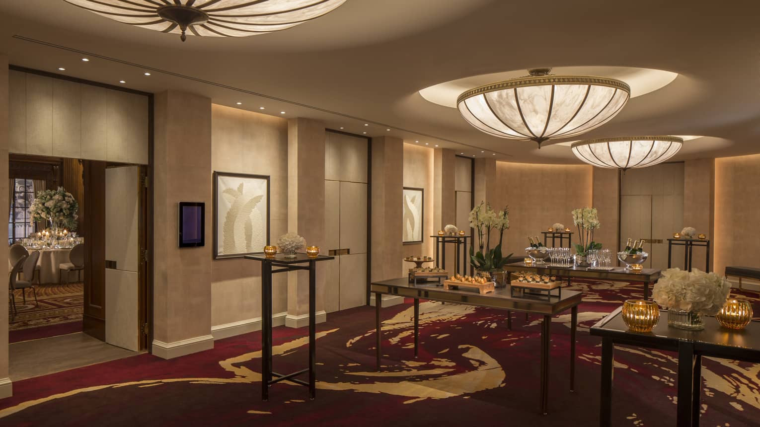 Cocktail reception, large dome lights over small tables with appetizers by door to adjoining ballroom