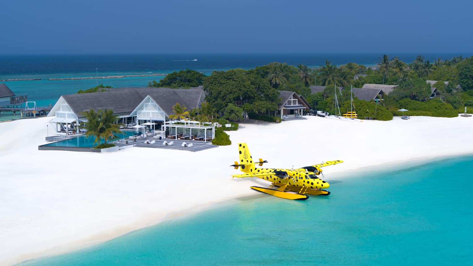 Flying Boxfish Seaplane prepares for takeoff from Resort, bungalows in background