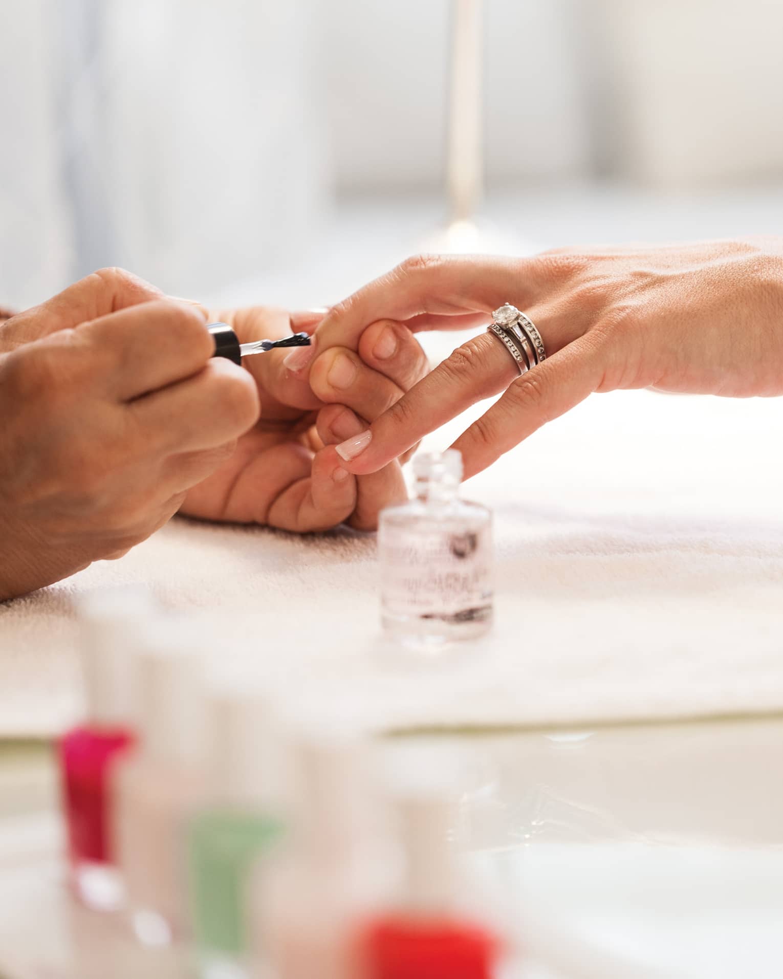 Close-up of woman in white robe getting clear polish manicure at spa table