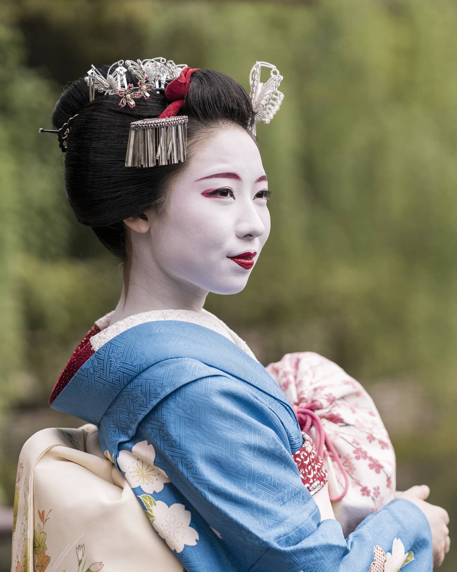 Woman dressed as traditional maiko (apprentice geisha) outdoors in the garden