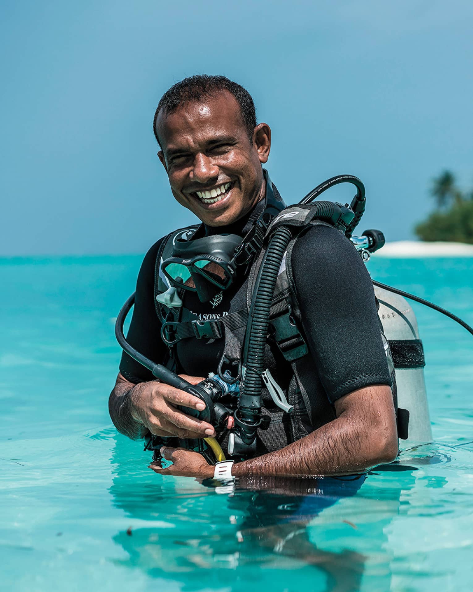 Smiling Dive Manager Ibrahim Nazeer with scuba gear in the crystal clear waters of the lagoon