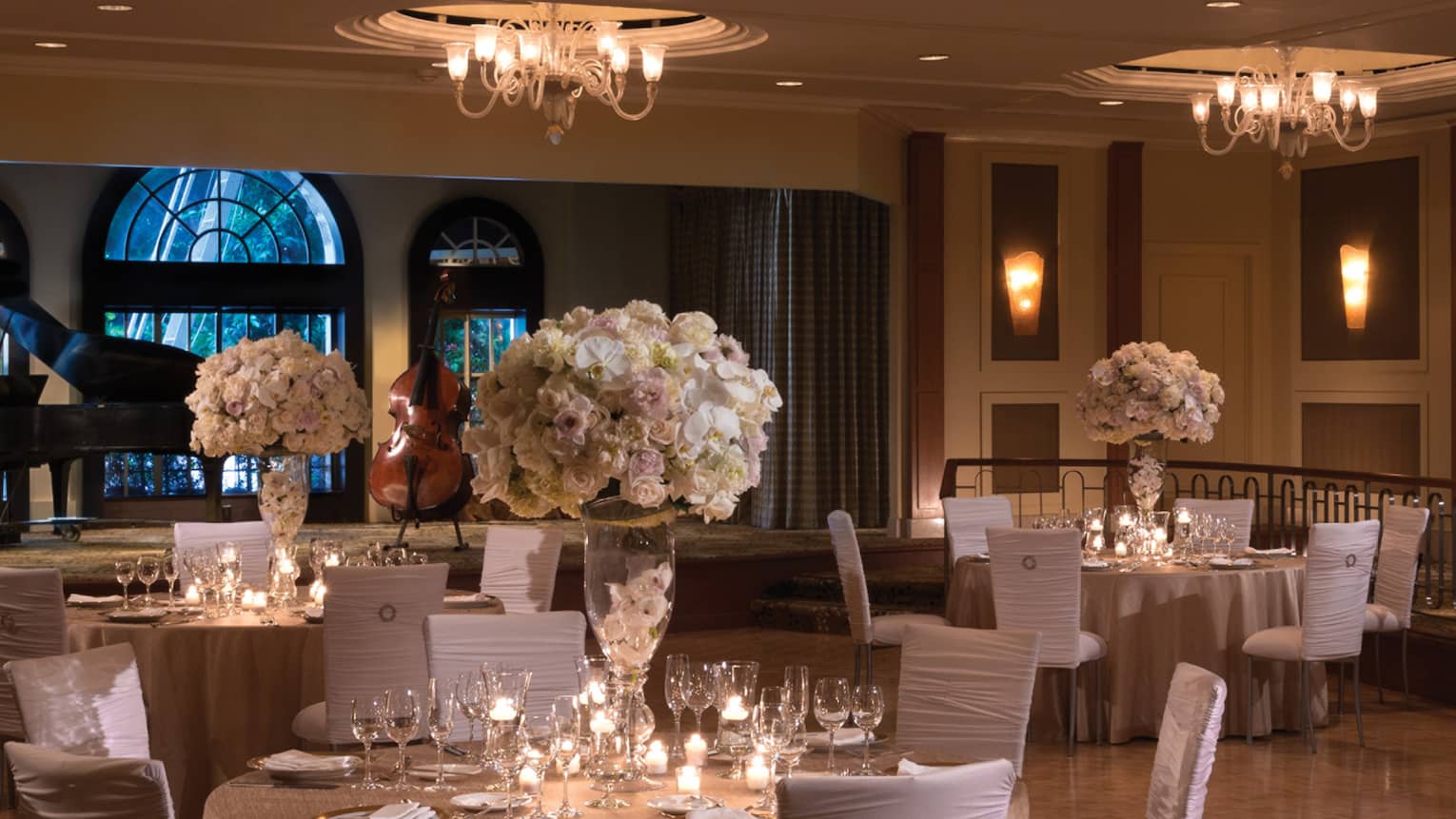 Elegant wedding reception tables with white chairs, flowers on ballroom floor