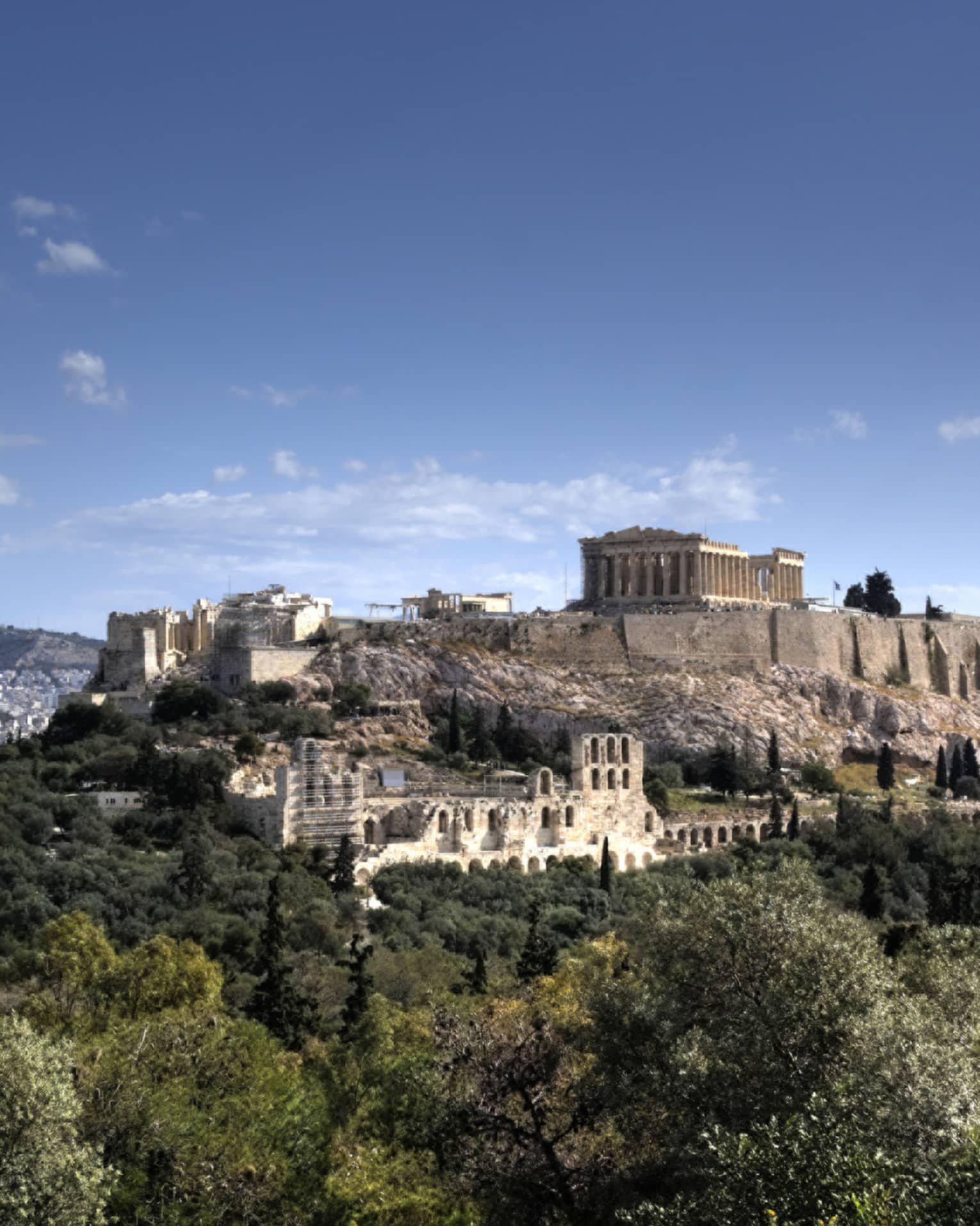 Ancient ruins of Acropolis on mountain surrounded by greenery 