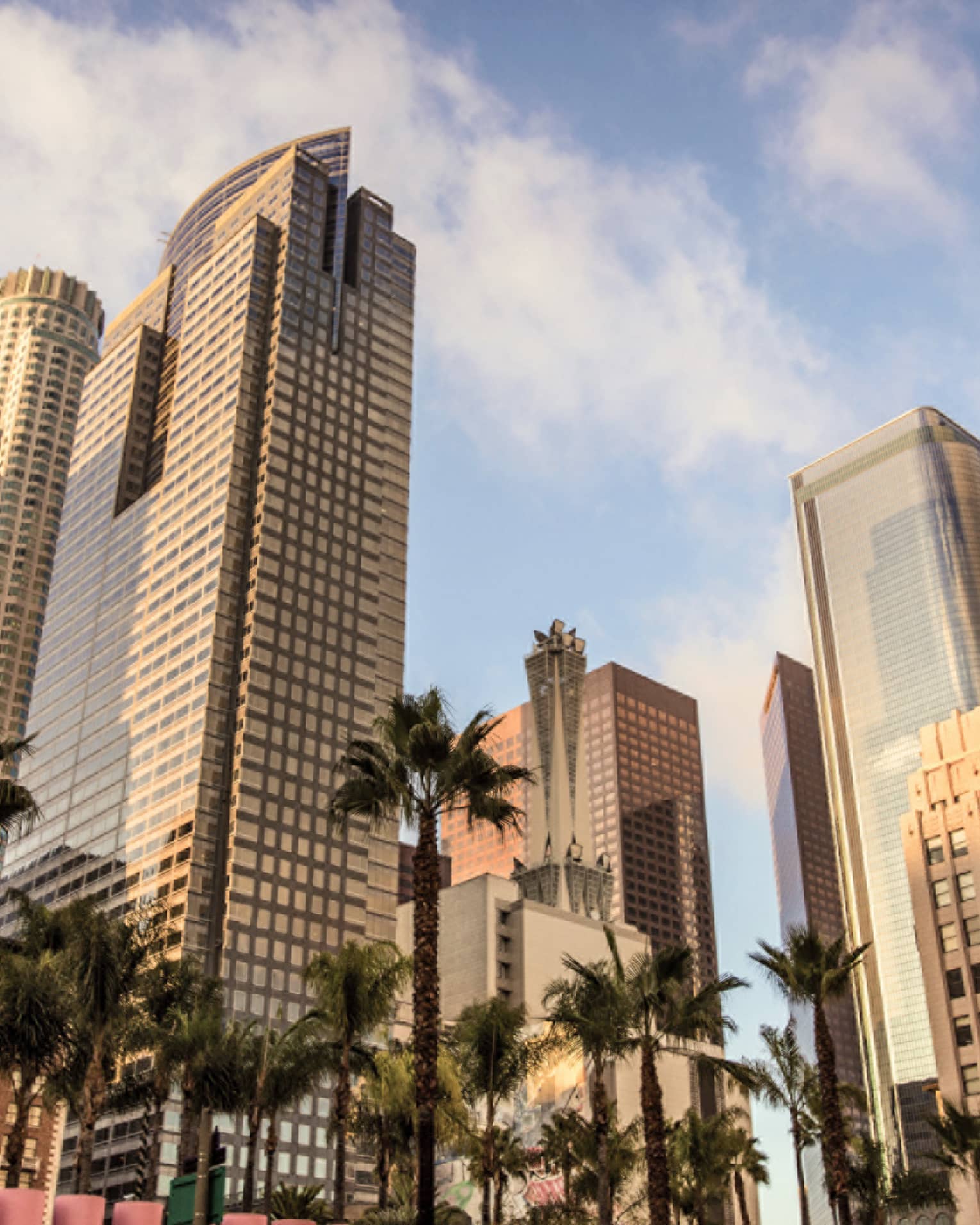 Tall downtown Los Angeles buildings, palm trees against blue sky 