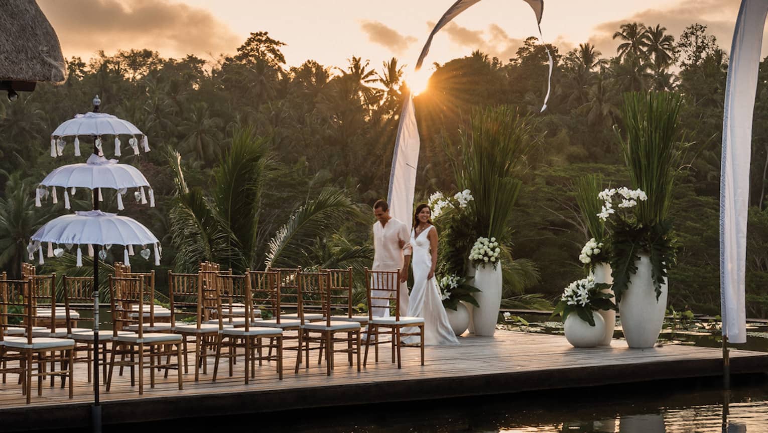 Wedding ceremony on platform over pond at sunset