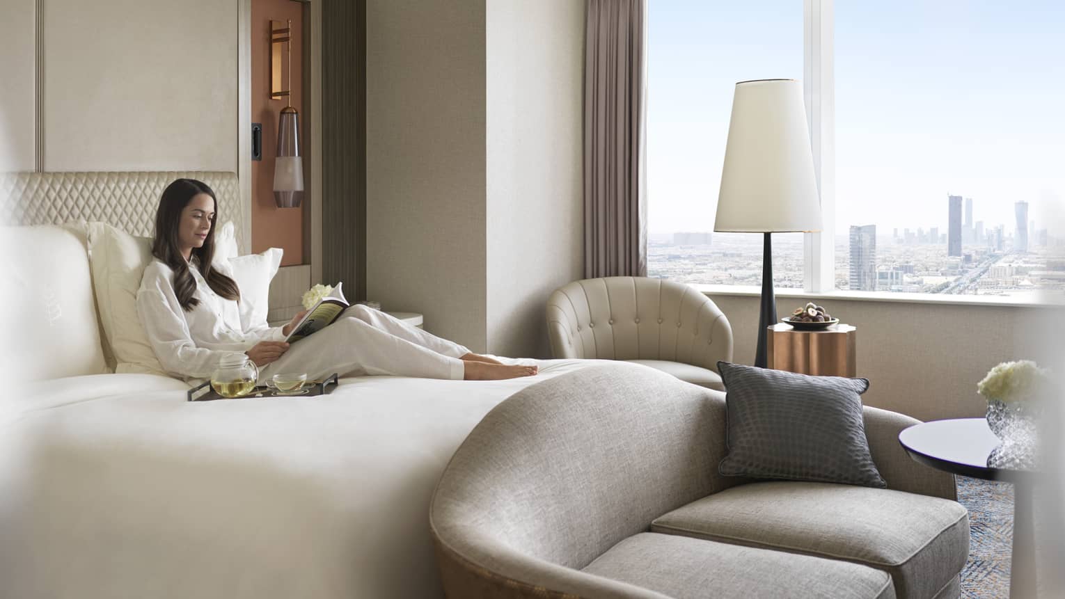 Woman reads book on bed in Four Seasons Executive Suite