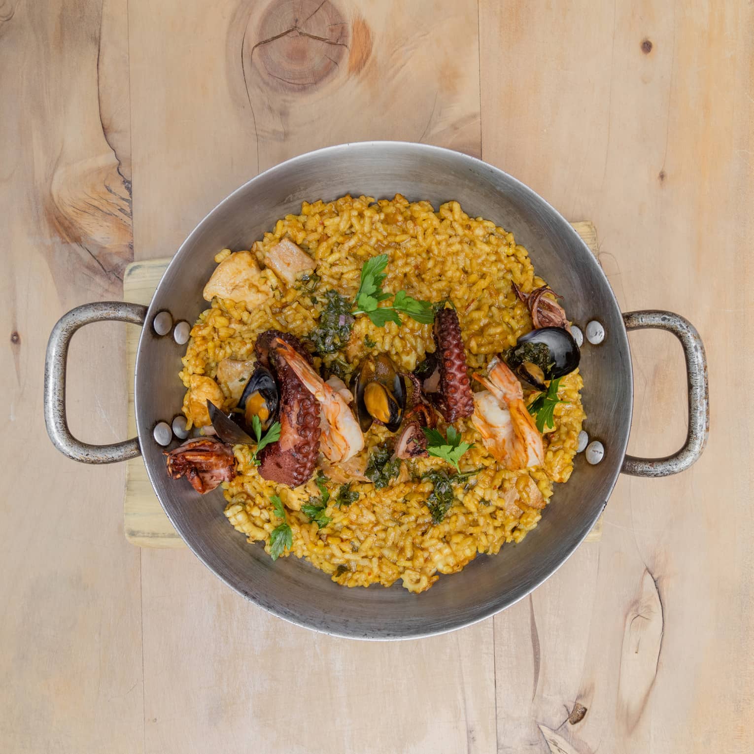 Paella served with yellow rice and sliced meats.