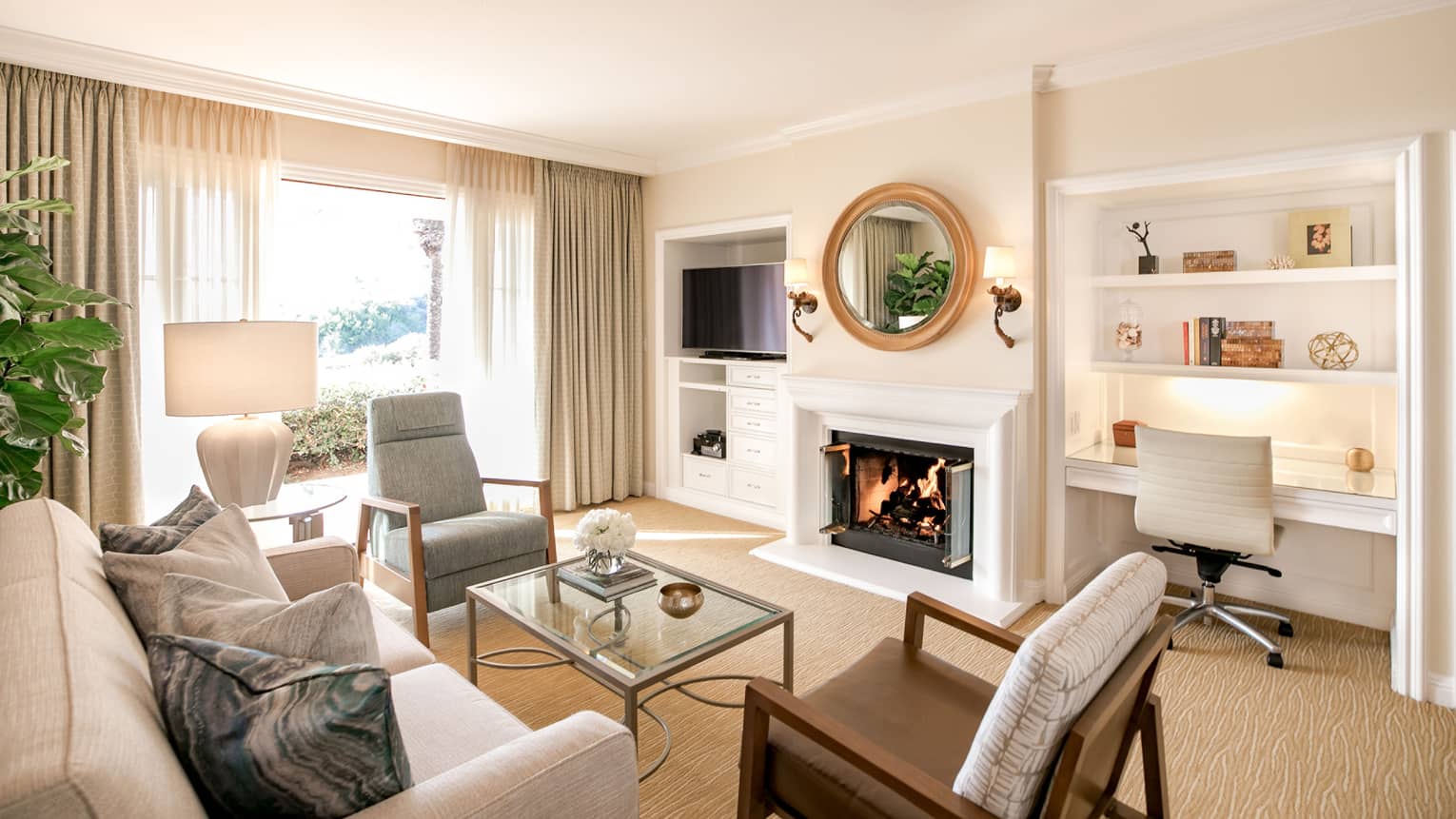 Sunny, modern villa seating room with white fireplace under round mirror, by built-in desk