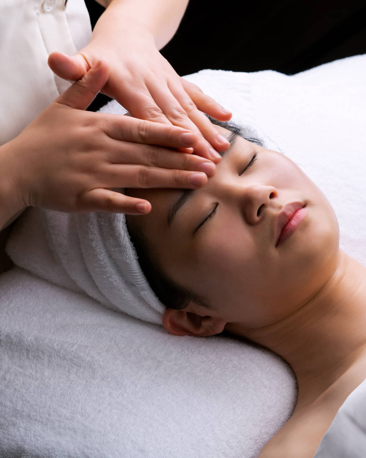 Spa staff places hands on woman's forehead during Anti-Oxidant Facial
