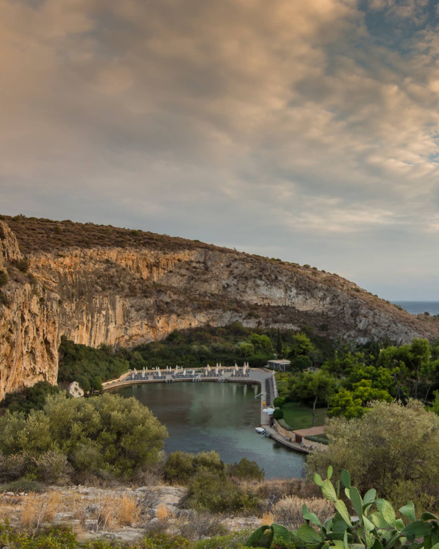 View of Vouliagmeni with rocky hill, green trees and shrubs overlooking ocean
