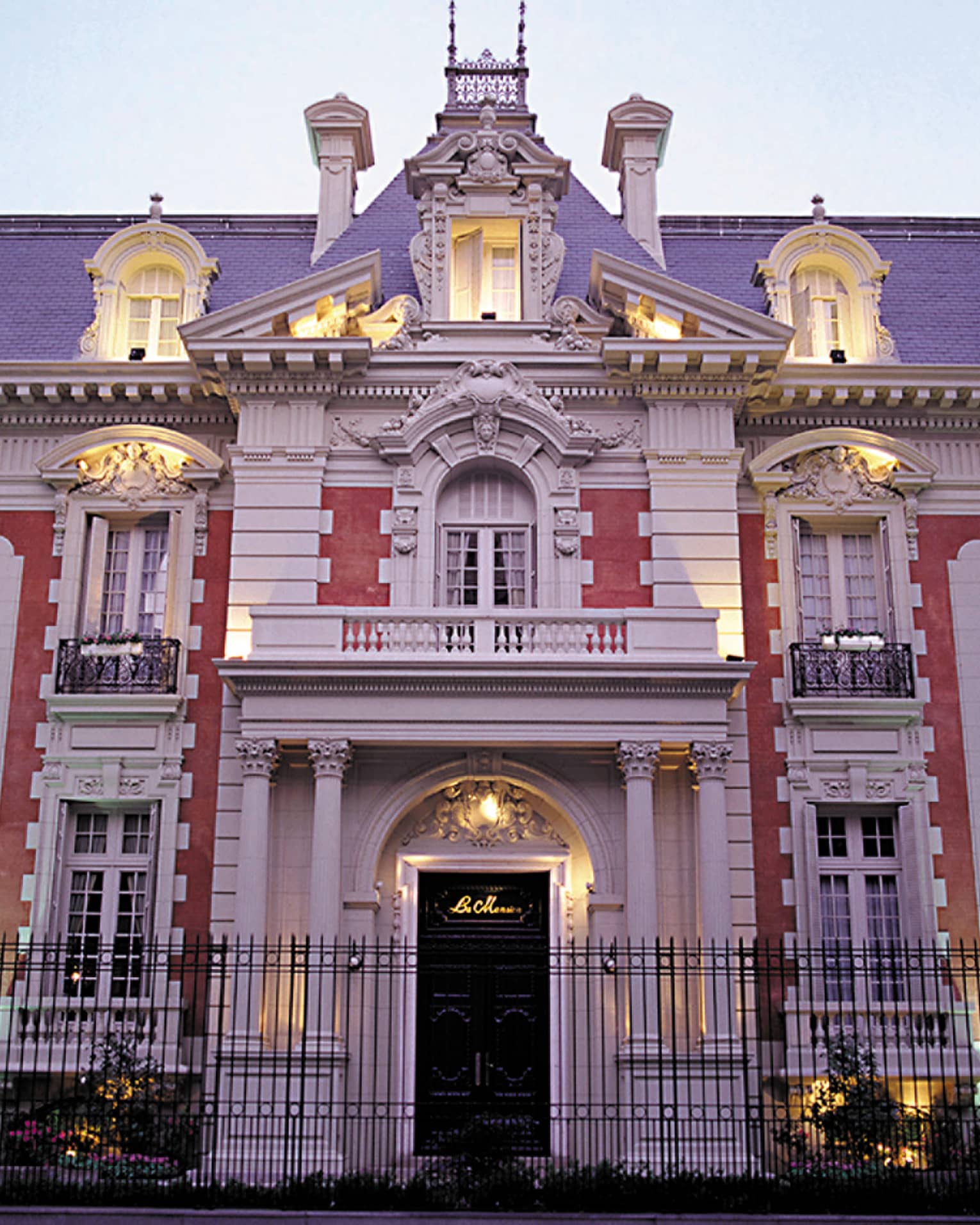 Four Seasons Buenos Aires hotel La Mansión historic exterior with lights at dusk, black fence in front