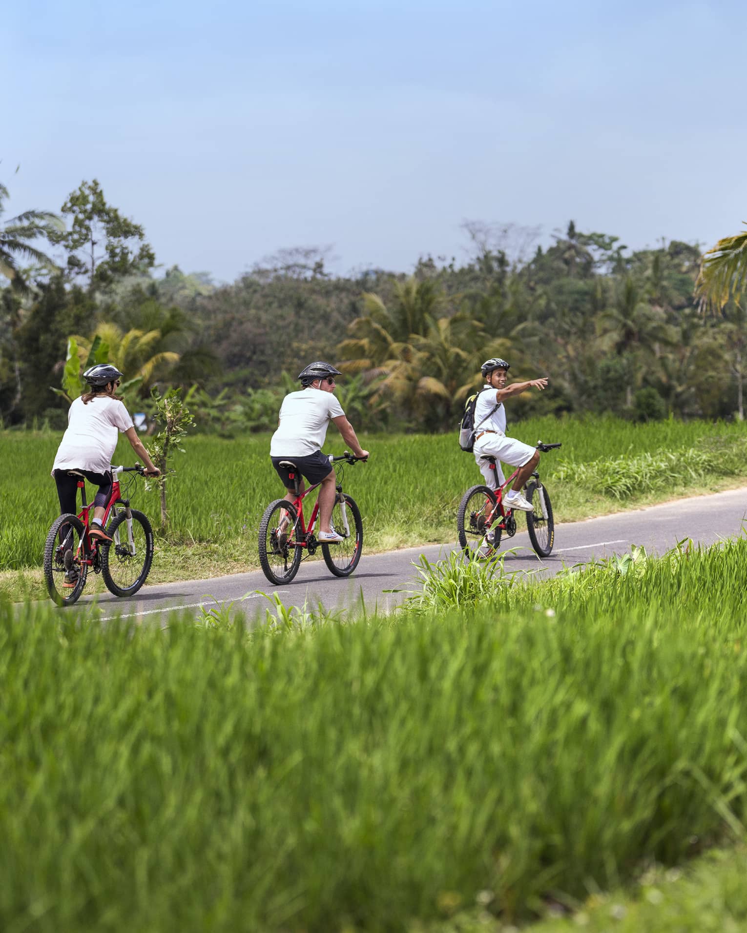 Four seasons guests bike along a paved path near four seasons hotel bali at sayan