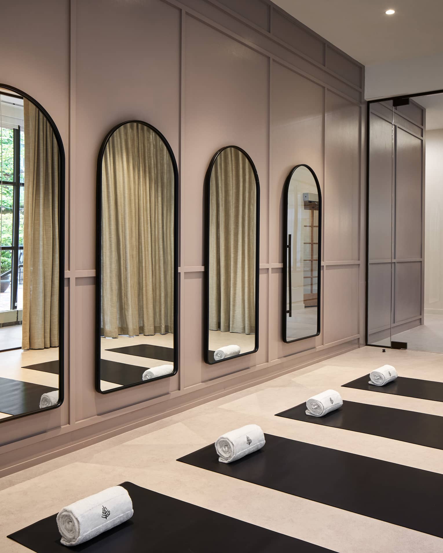 Yoga mats in a yoga studio with mirrors on the wall.