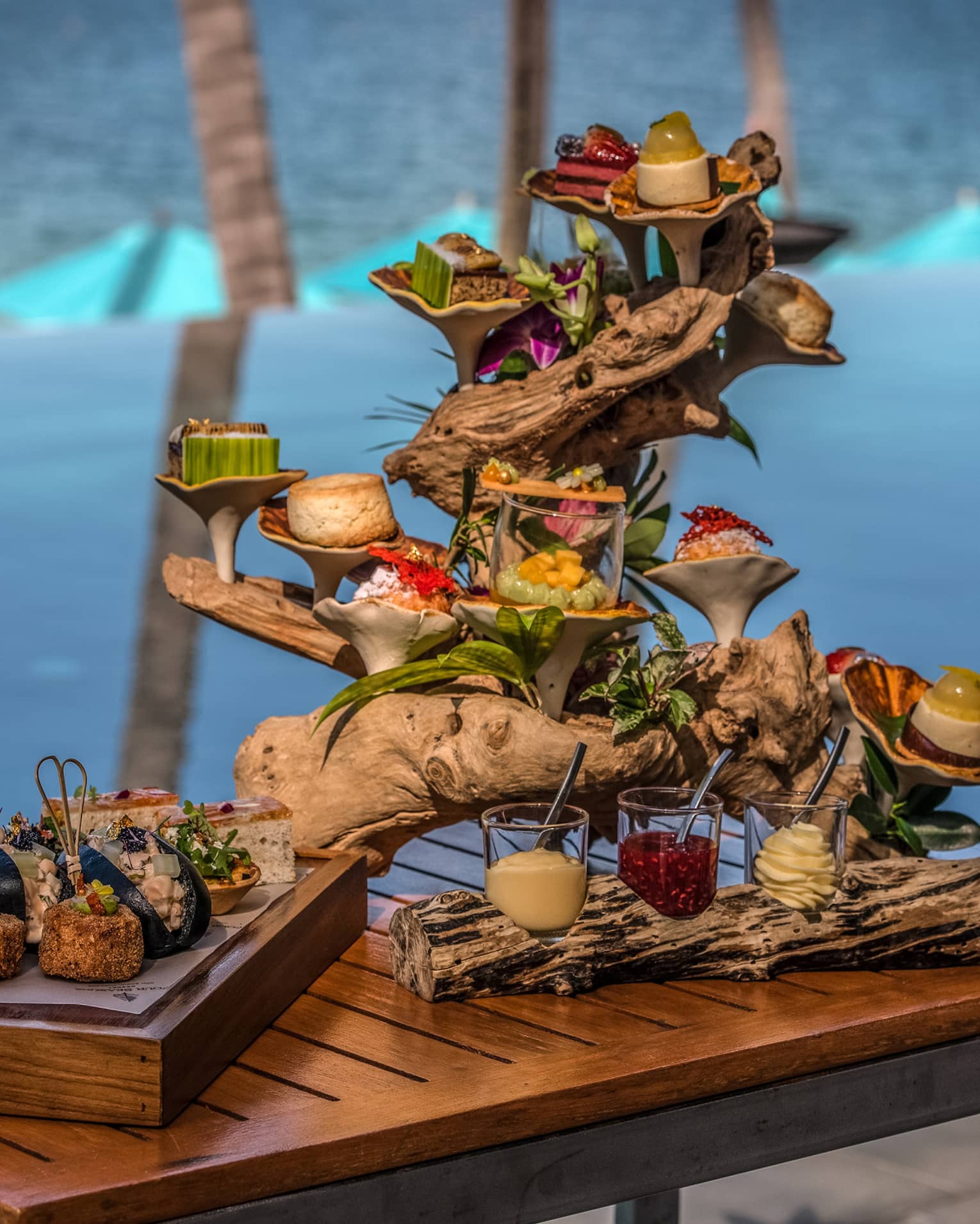 Afternoon tea spread with sweets and savouries presented on a piece of driftwood