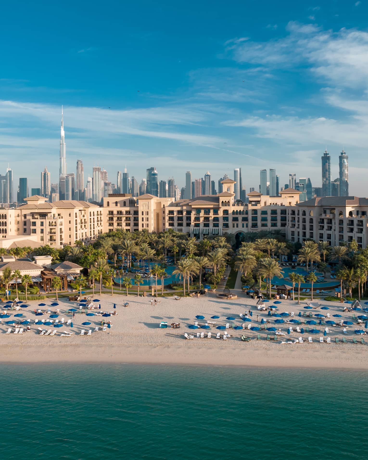 An aerial view of Dubai Jumeirah Beach of the ocean, with the city skyline behind.