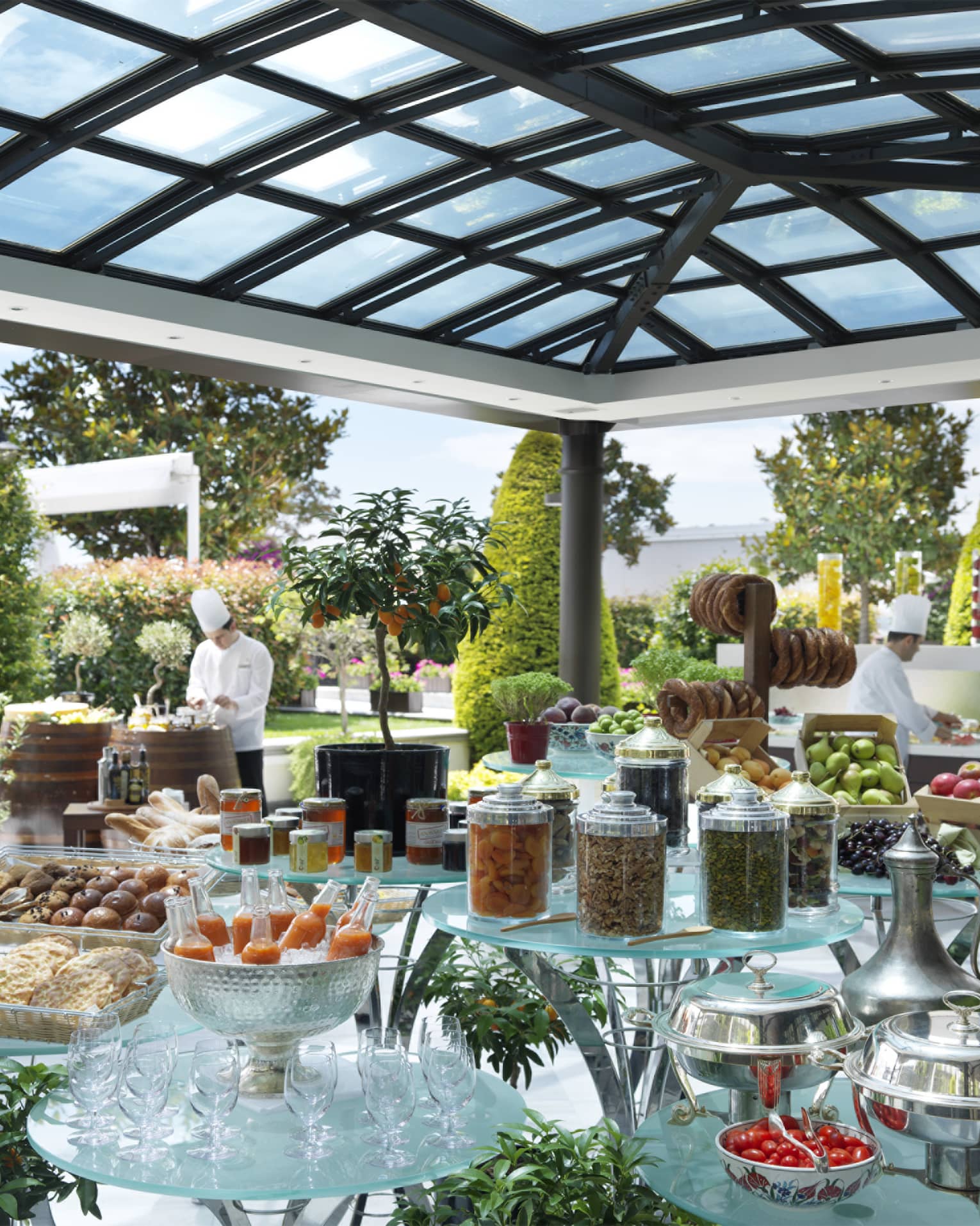 Brunch buffet on glass display on outdoor patio, chefs in white uniforms