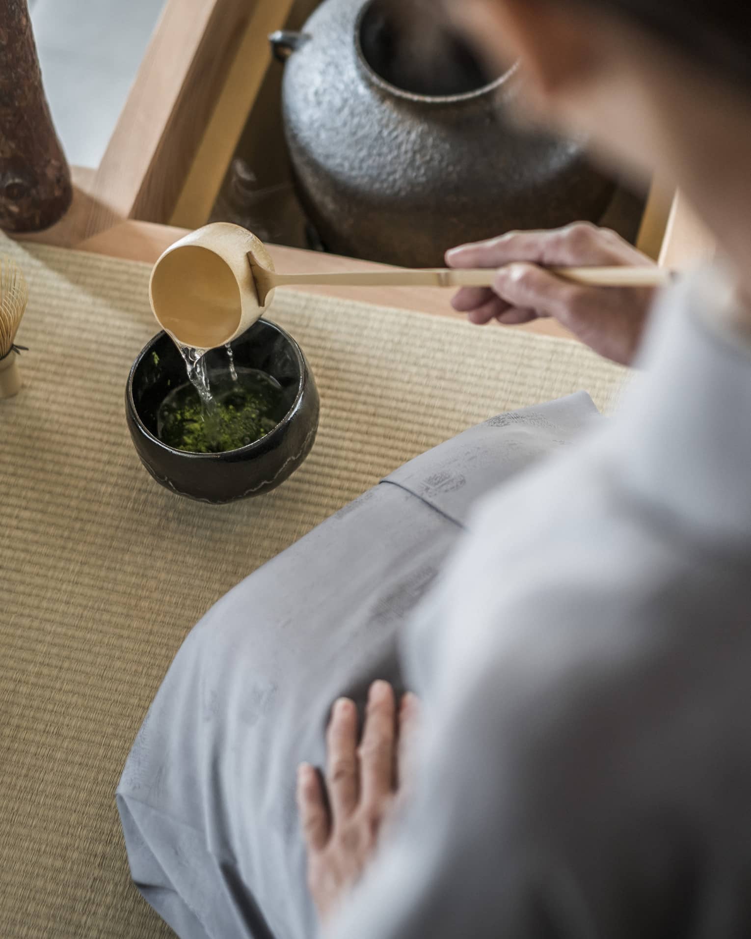 Woman kneels and pours tea from ladle during Tea Ceremony