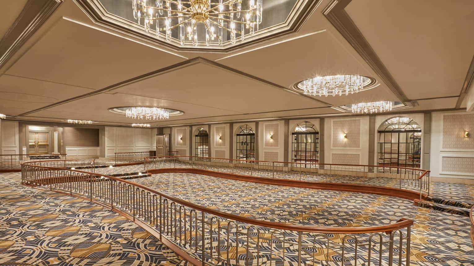 Curved railing in large, empty, carpeted Le Grand Trianon ballroom