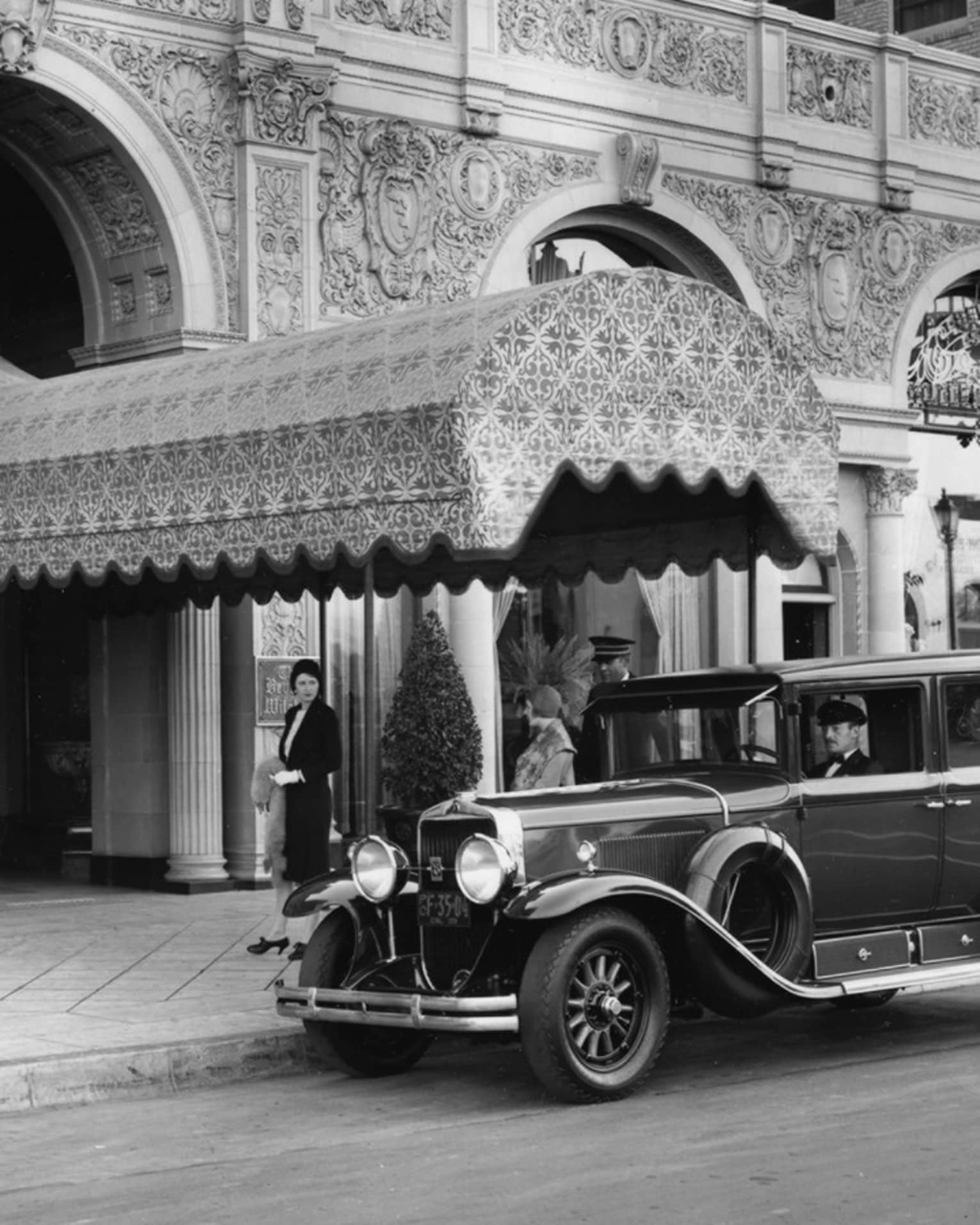 Historic photo of Beverly Wilshire entrance with car parked in front