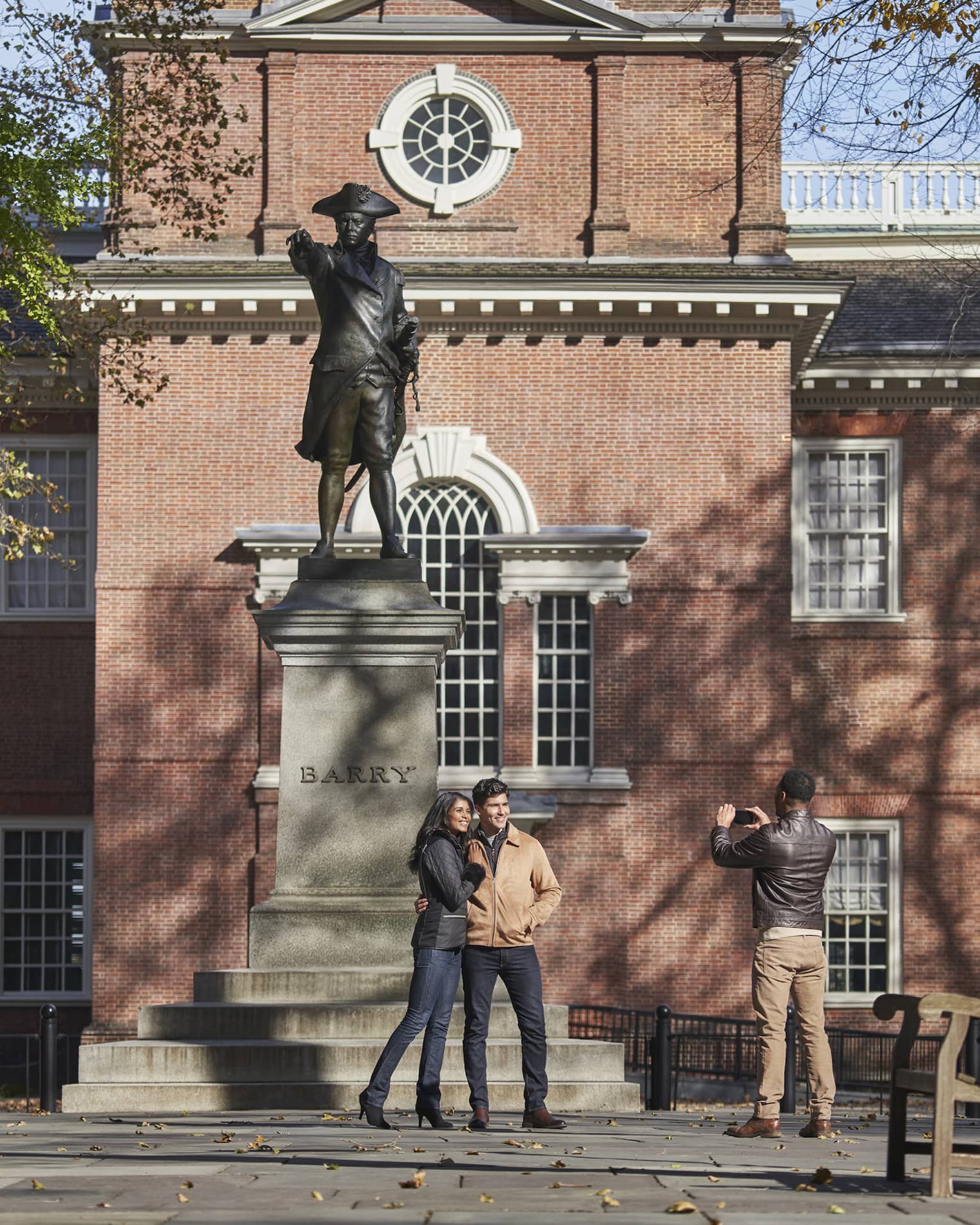 Couple poses for photo in front of statue and historic building