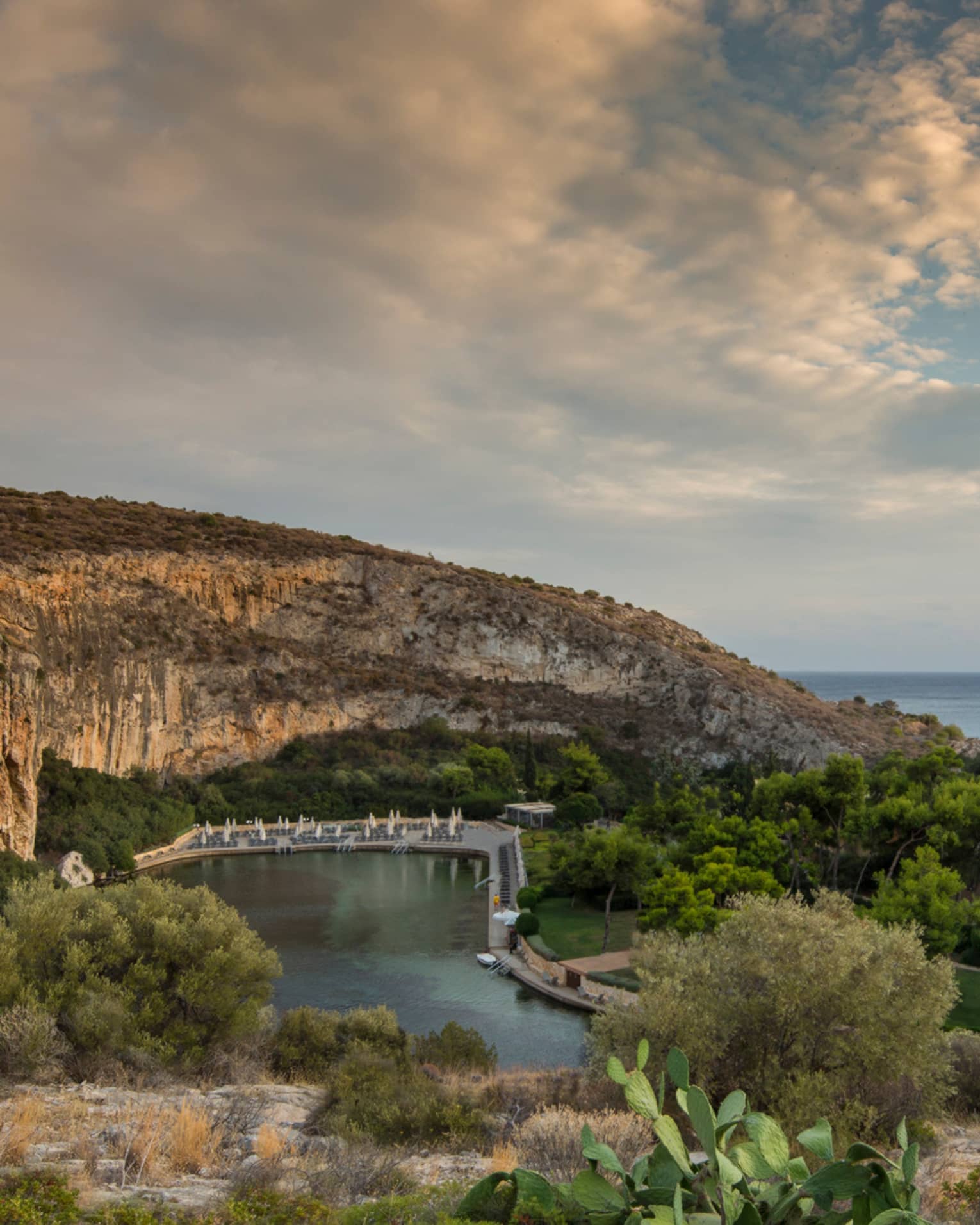 View of Vouliagmeni with rocky hill, green trees and shrubs overlooking ocean