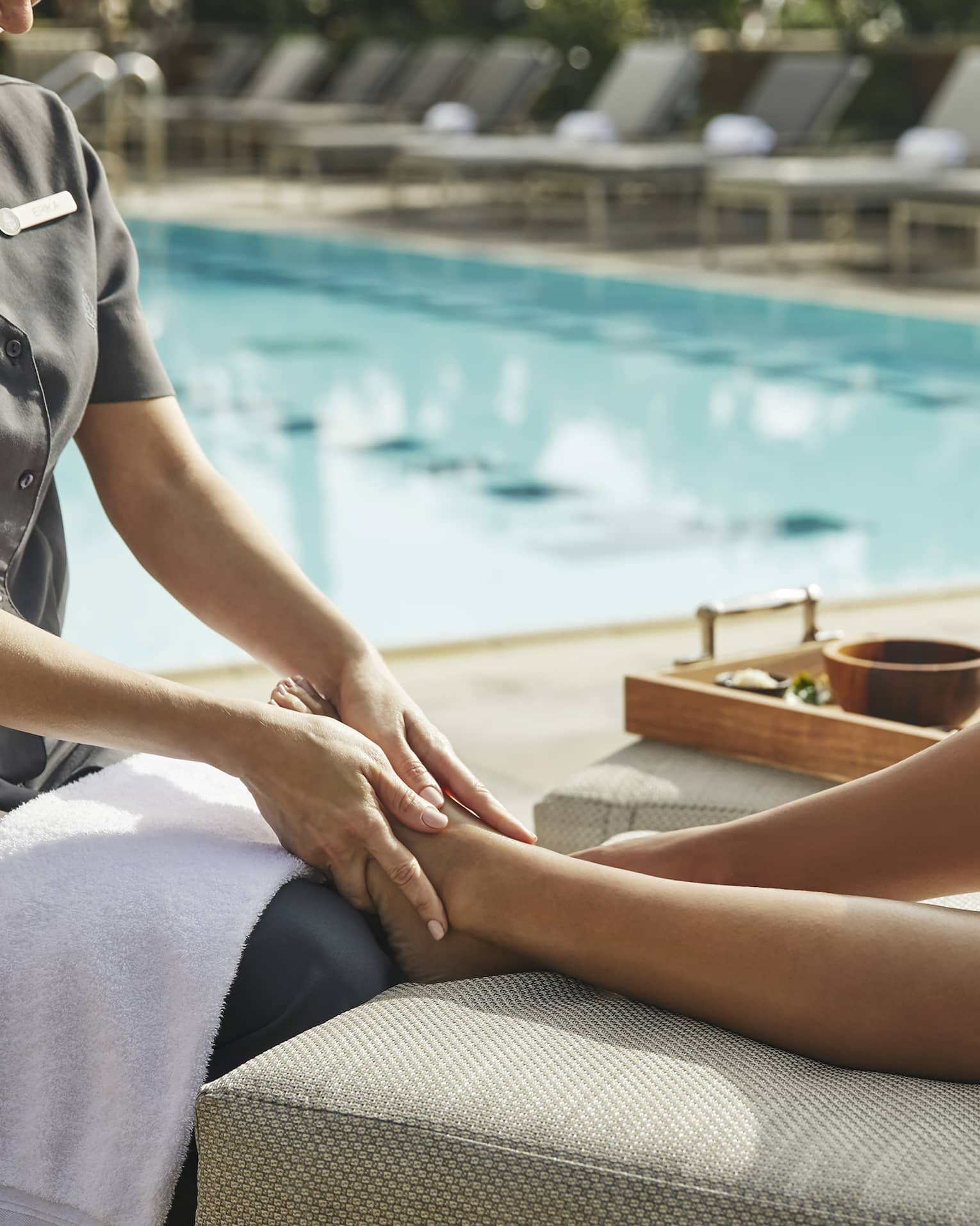 A person receiving a massage next to a pool outside.