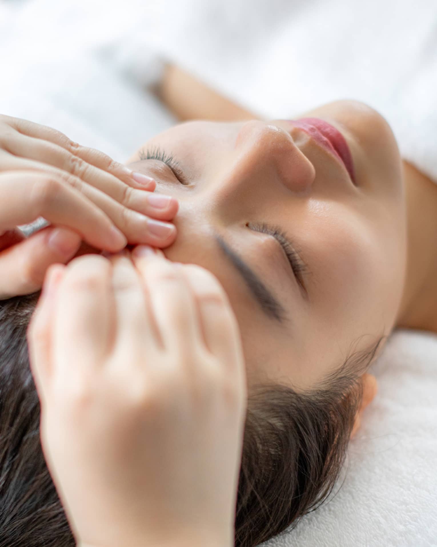 A woman getting a facial massage in a spa.