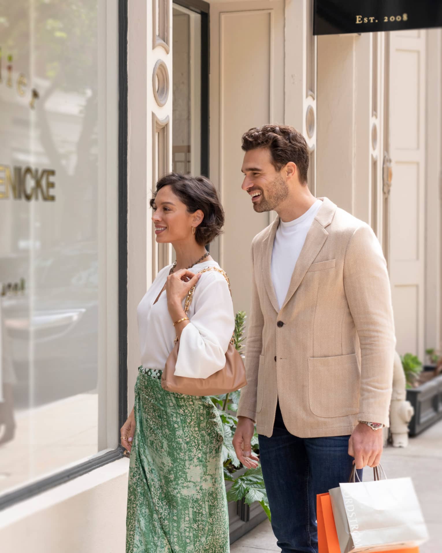 A couple admires a storefront together while shopping. 