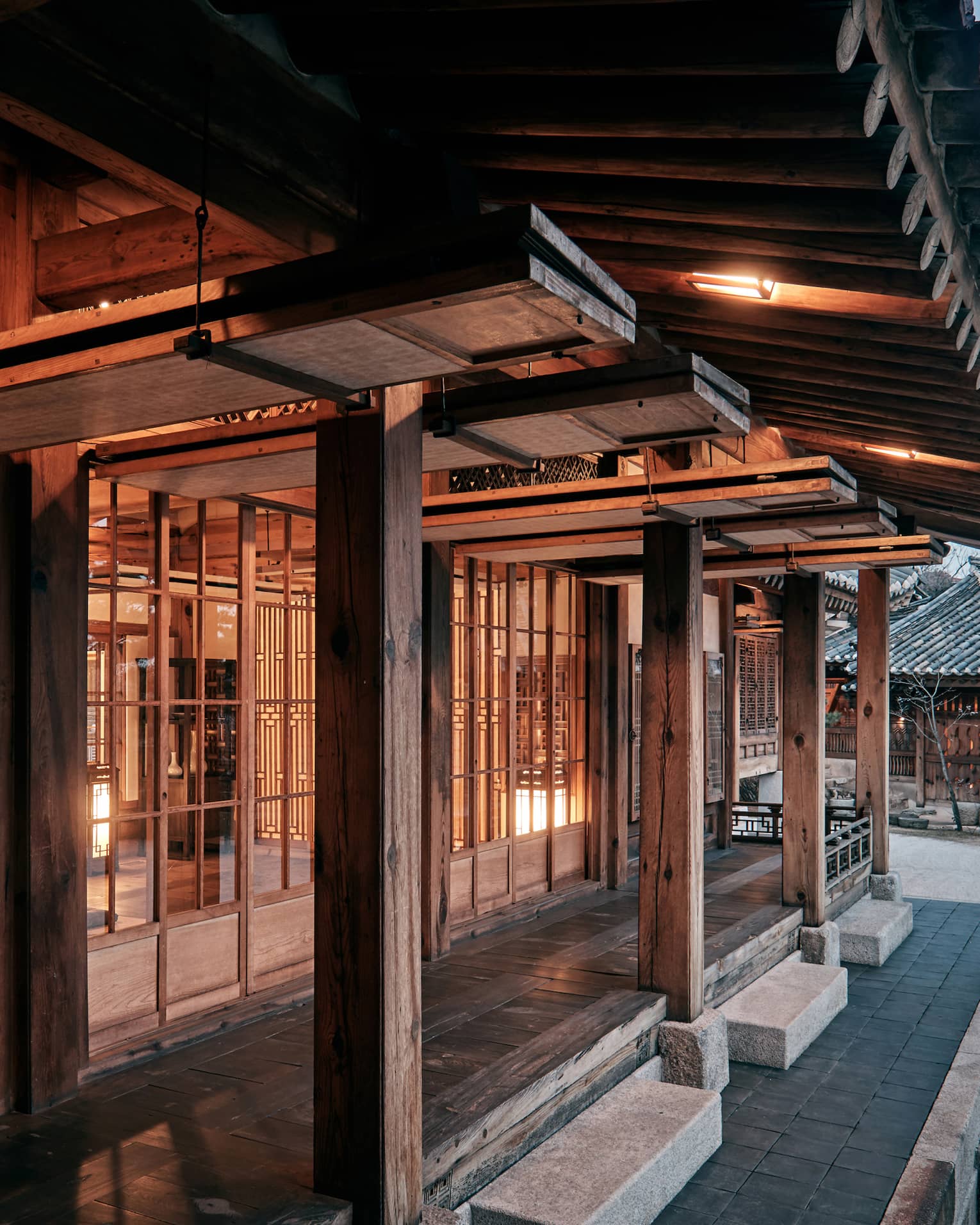 Korea Furniture Museum exterior, cement steps, rustic wood pillars outside windows with wood frames, lights