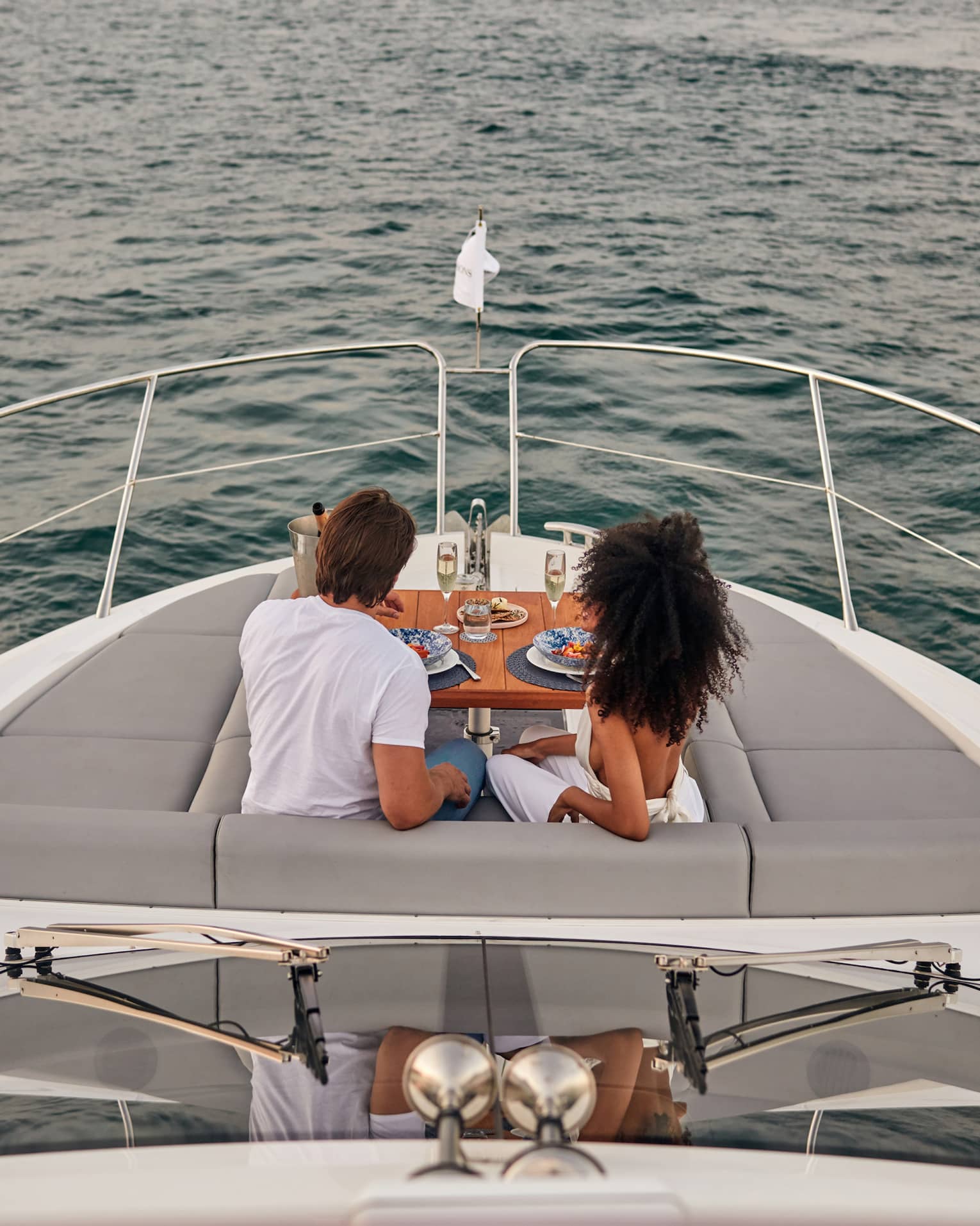 A man and woman eating food on the deck of a boat.