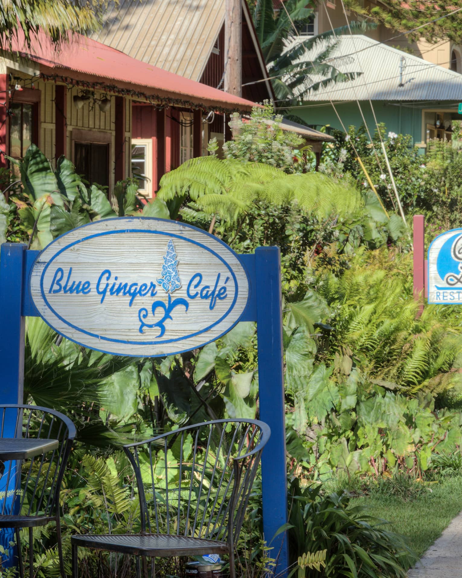 Garden patio table under Blue Ginger Cafe sign, path leading to more cafes and shops