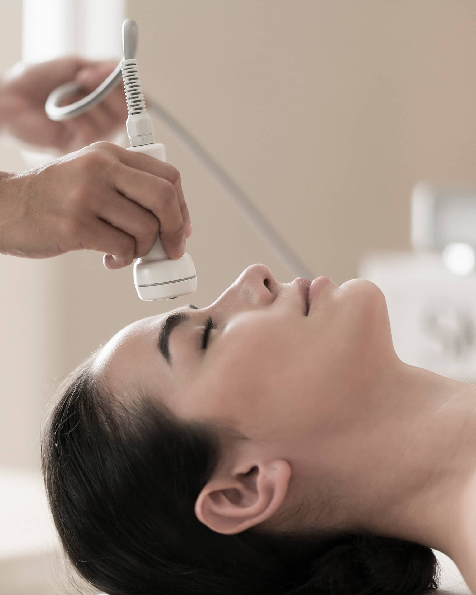 Spa attendant applies a facial to a guest