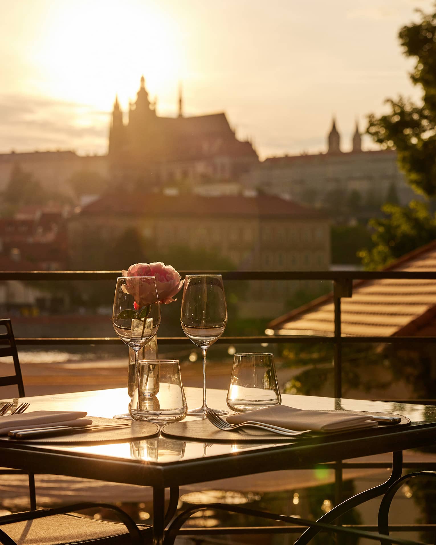 Terrace dining setup at sunset with view of Prague Castle in backdrop