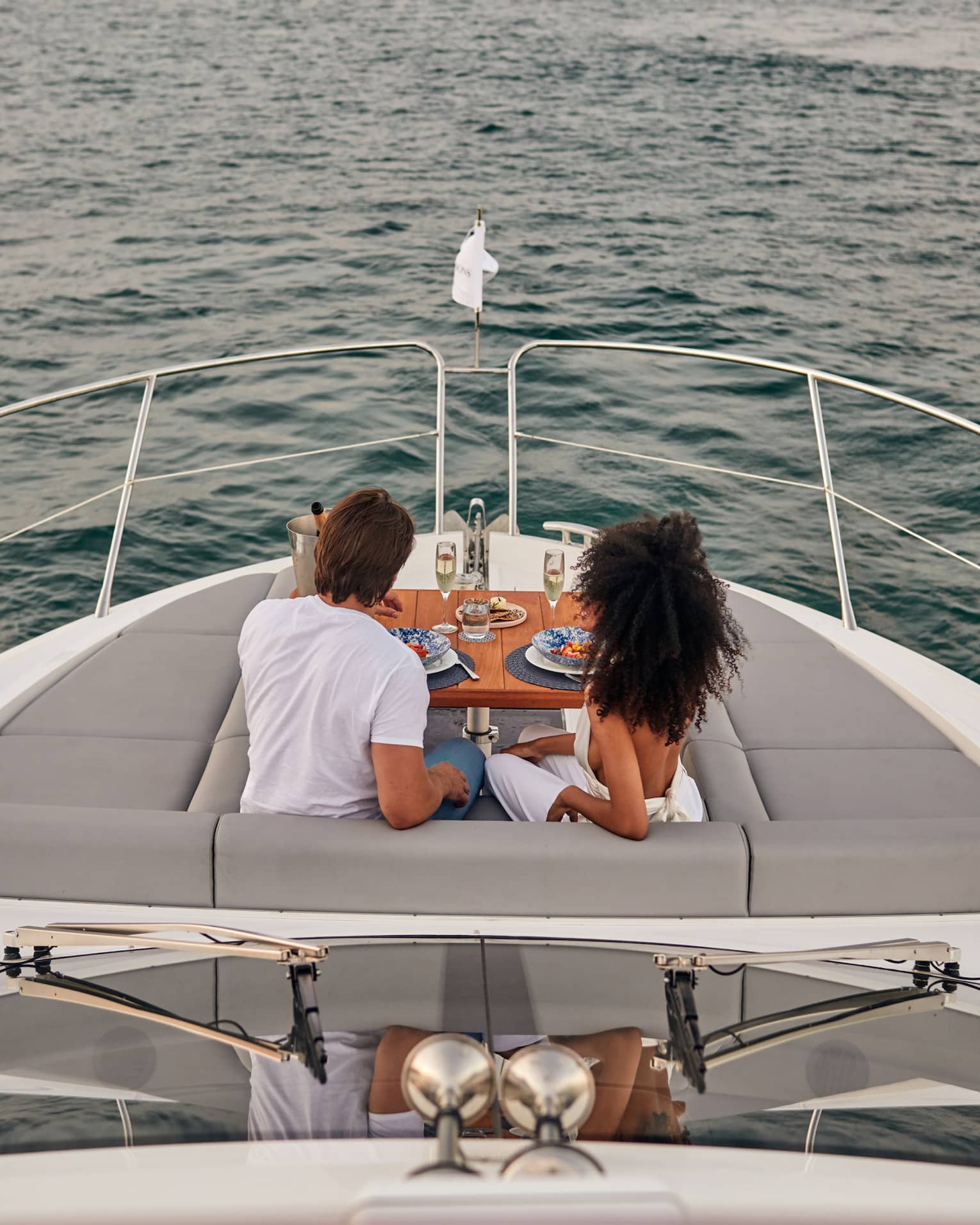 A man and woman eating food on the deck of a boat.