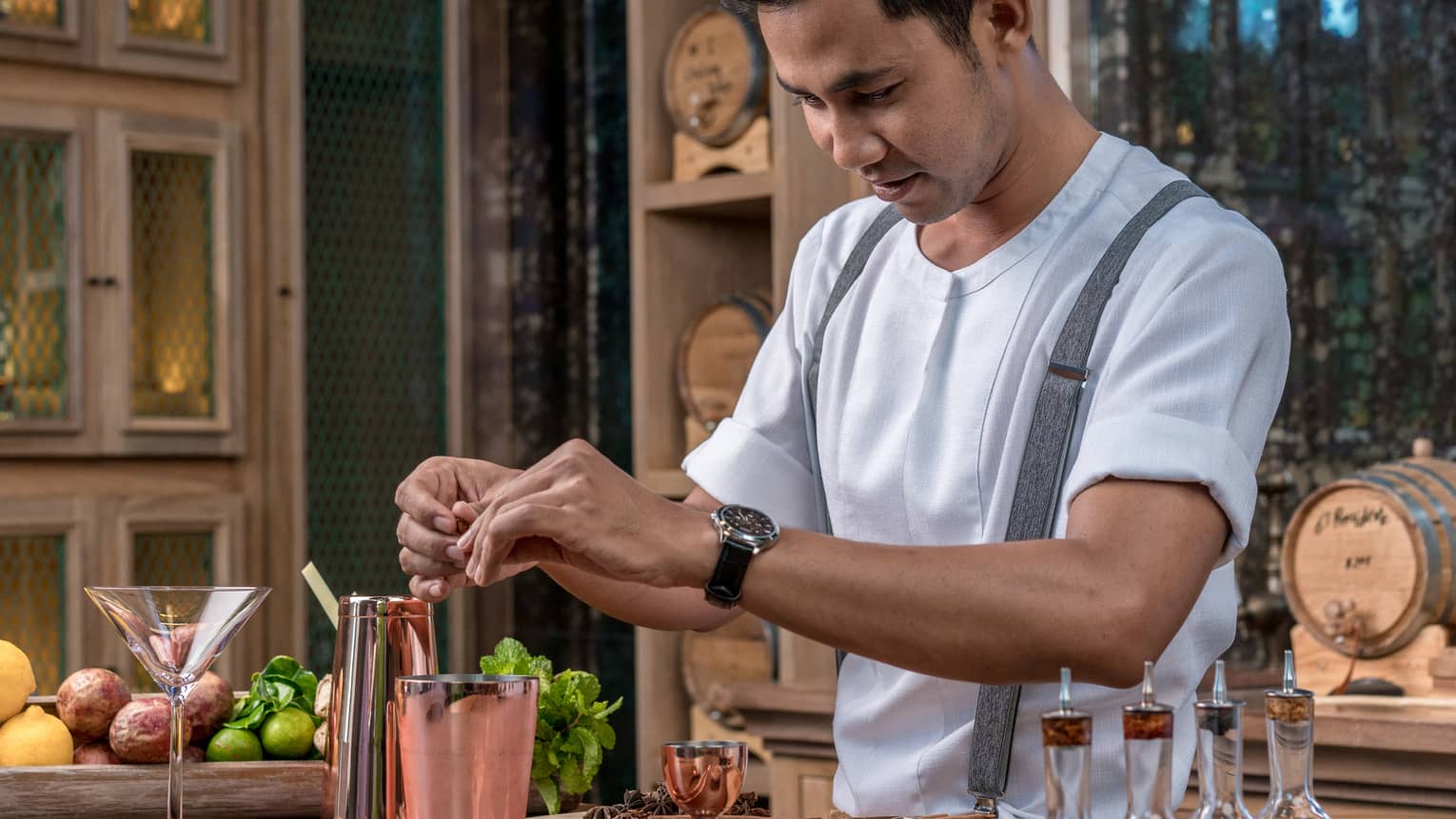 Bartender adds fragrant spices to a copper shaker in preparation for a cocktail 