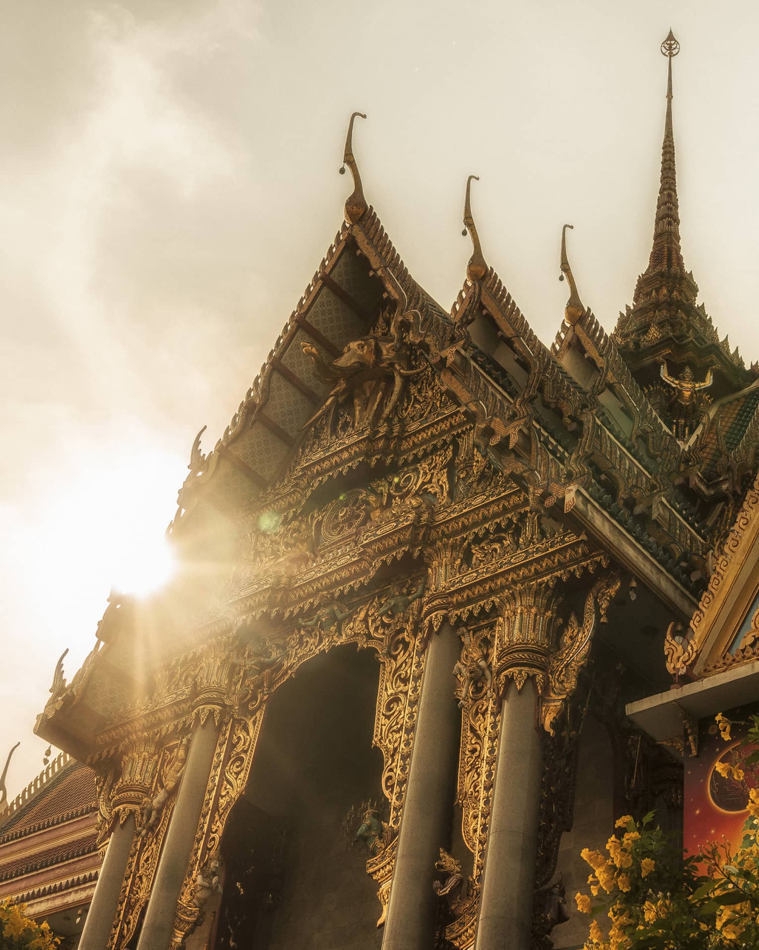 A Thai temple at sunrise, with ornate golden spires and chofahs, exuding tranquility.