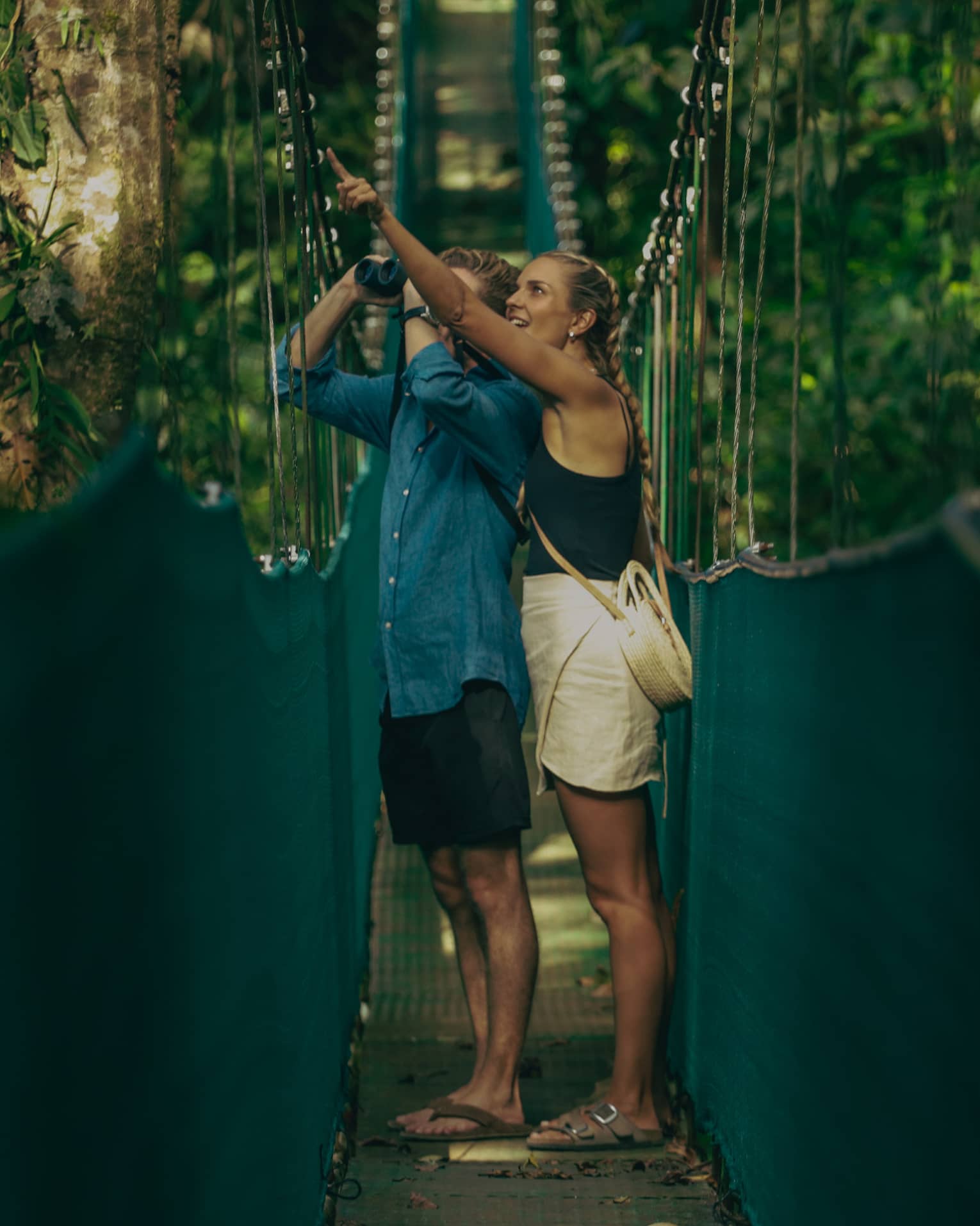 A man and woman walking along a hanging bridge.