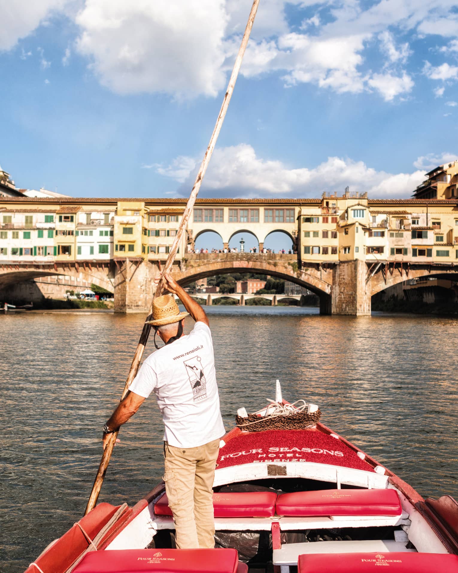 Man with long paddle steers Barchetto boat on Florence canal near bridge