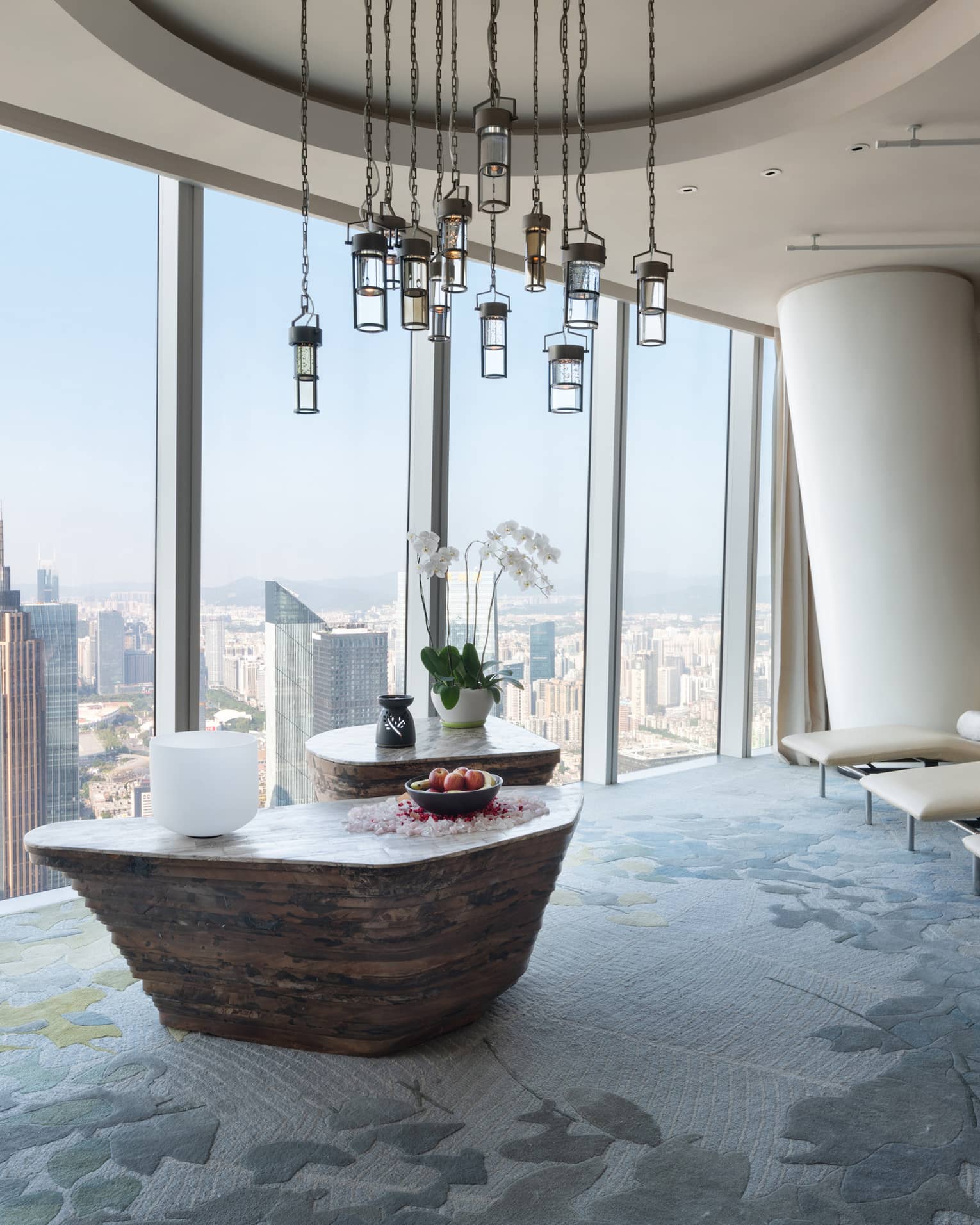 Large soaking tub filled with flower petals overlooking the cityscape from floor-to-ceiling windows