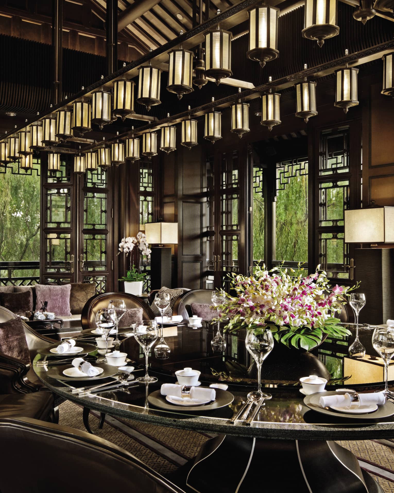 Large round, black, shiny dining table under lantern chandelier at Jin Sha