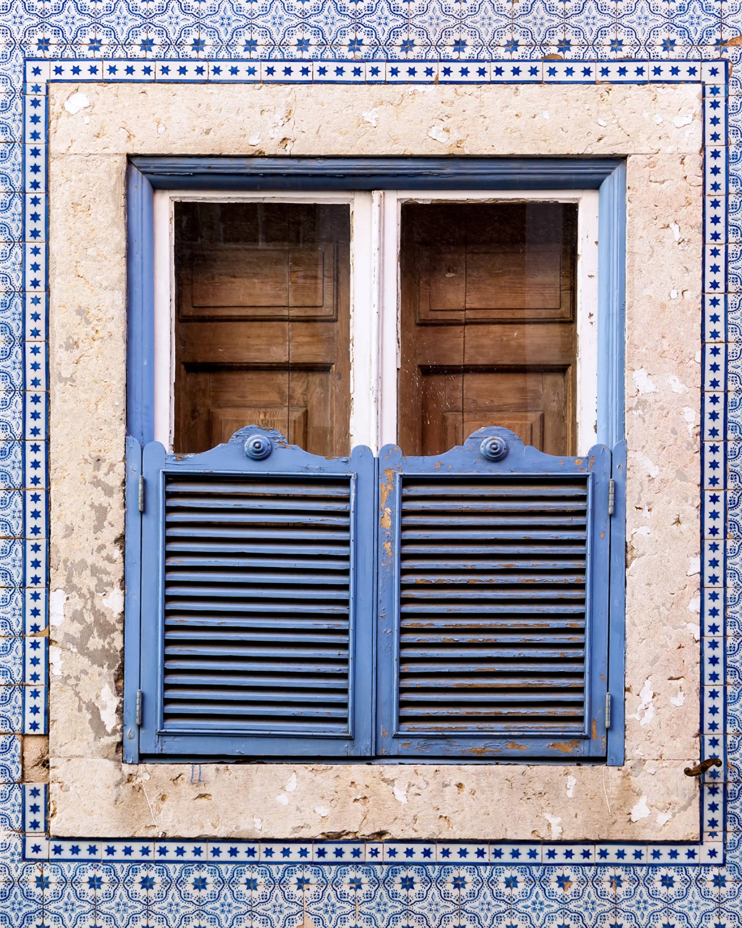 A blue wall and window covered in blue and brown doors.