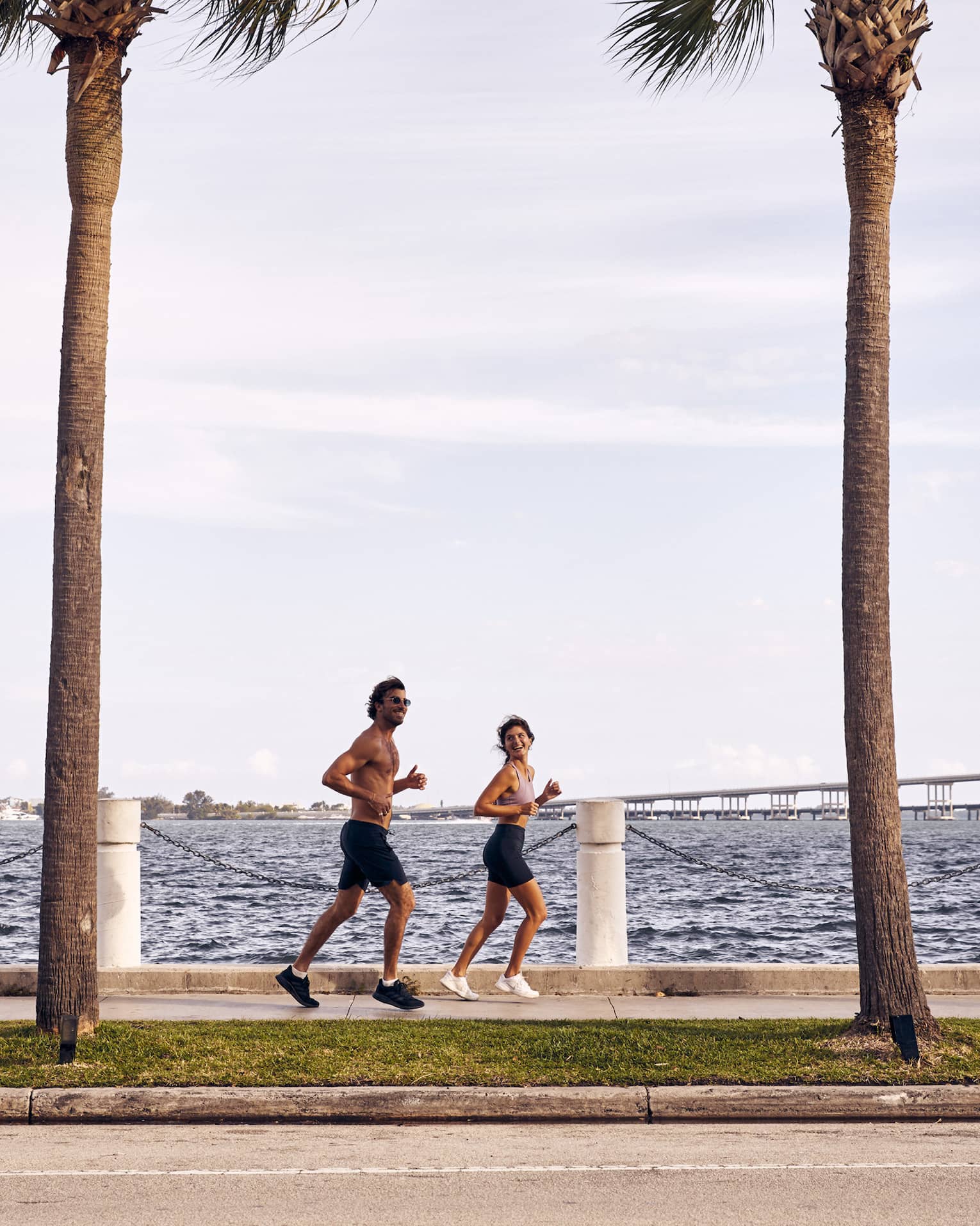 Man and woman running on sidewalk next to water