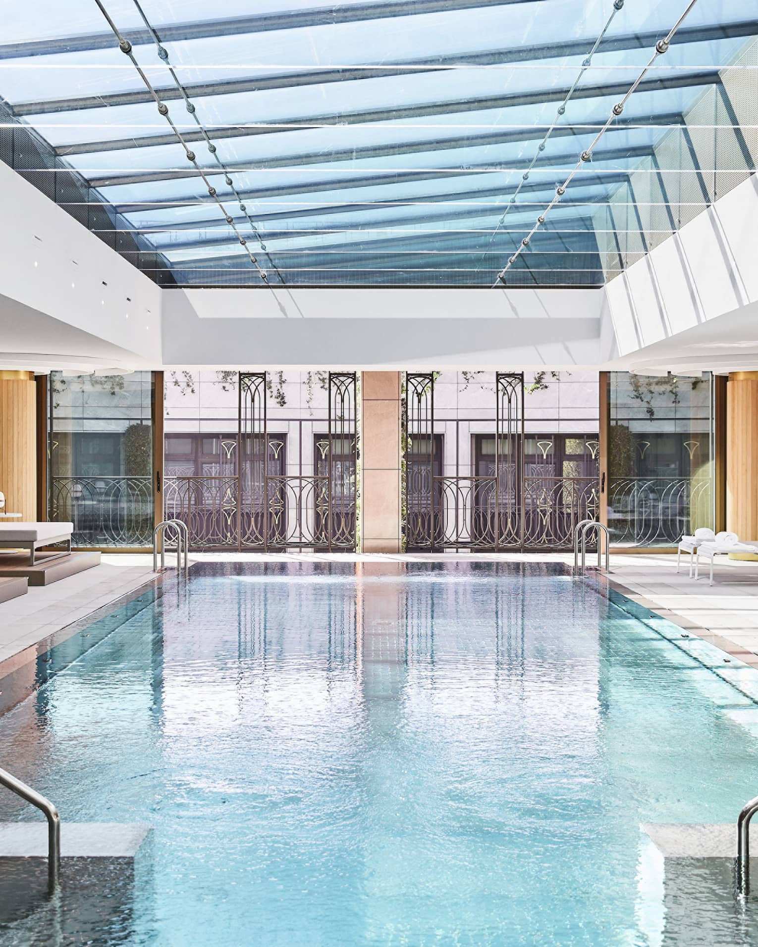 Rectangular indoor pool with two staircases into the pool, glass window ceiling